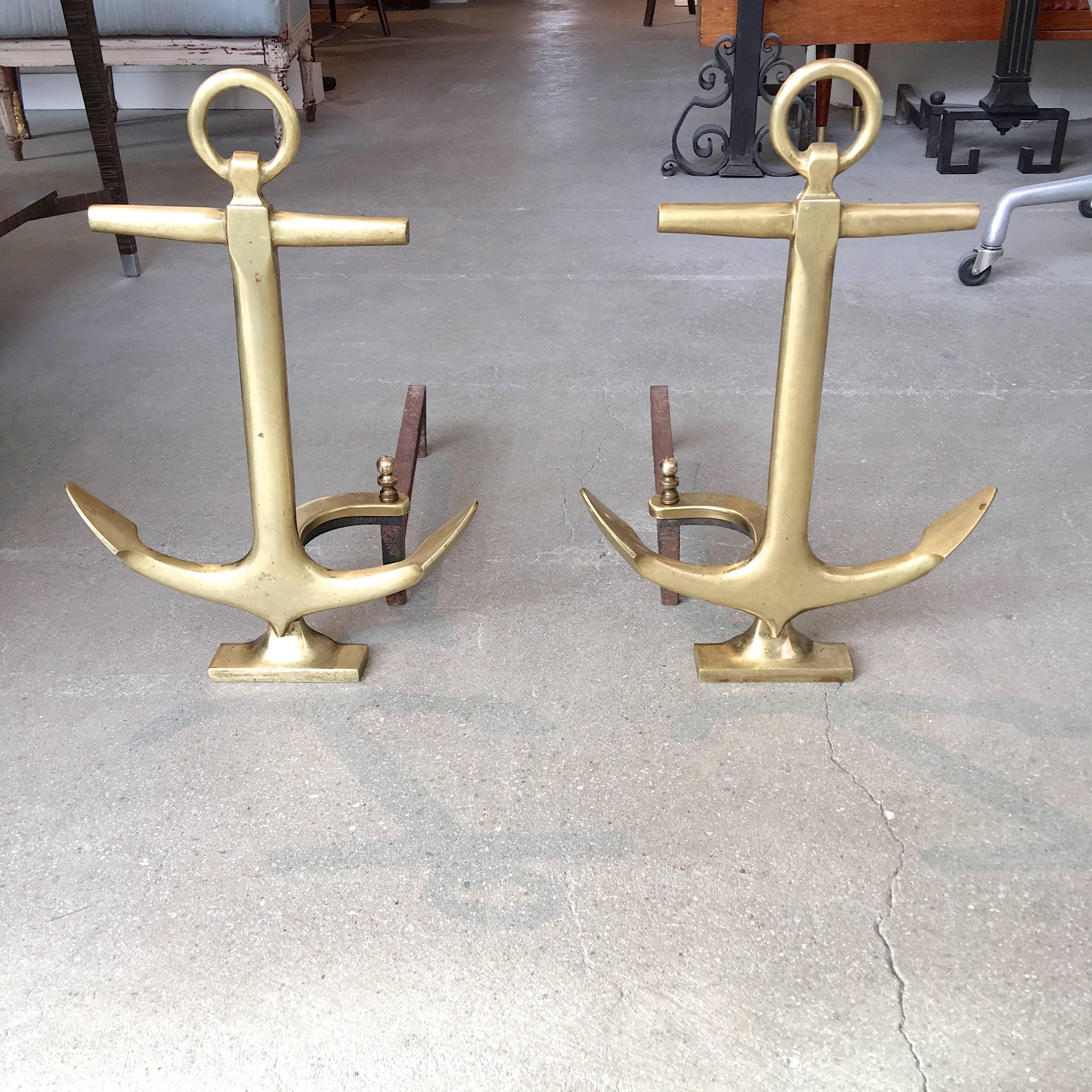 Pair of mid-20th century cast brass andirons in the form of ships' anchors, each having wrought iron fire log holders. This nautical themed pair is especially nice in that the curved section of the wrought iron is clad in a brass sheath as well as