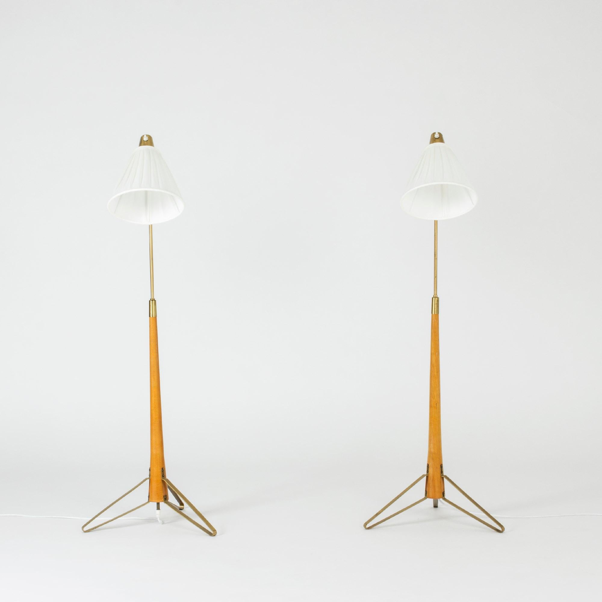 Pair of brass floor lamps by Hans Bergström, with beech handles and elaborately folded brass feet. 

The lamps have the same lowest height, 116 cm, but can be adjusted to different heights, 137.5 and 146.5 cm.