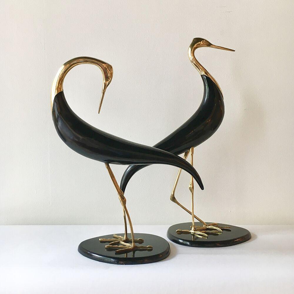 Pair of polished brass and ebonised wood table sculptures depicting birds in different positions set on ebonized bases, 1970s. The birds are stork like in appearance.