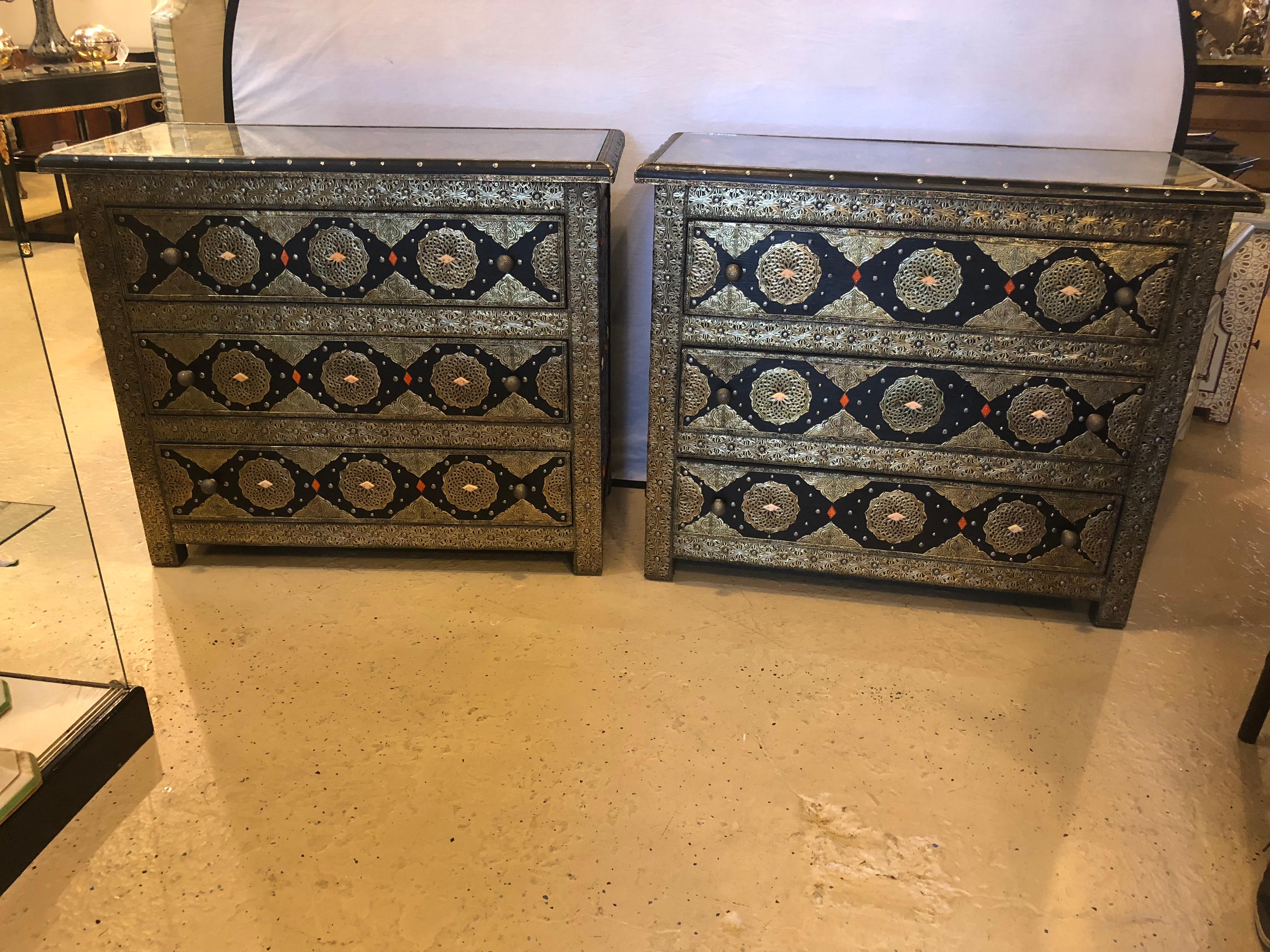 Pair of brass and ebony camel bone inlaid Moroccan commode or nightstands. These exceptional chests depict and compliment the Hollywood Regency era at its finest. Each featuring amazing intricate latticework on silver-toned metal and brass and