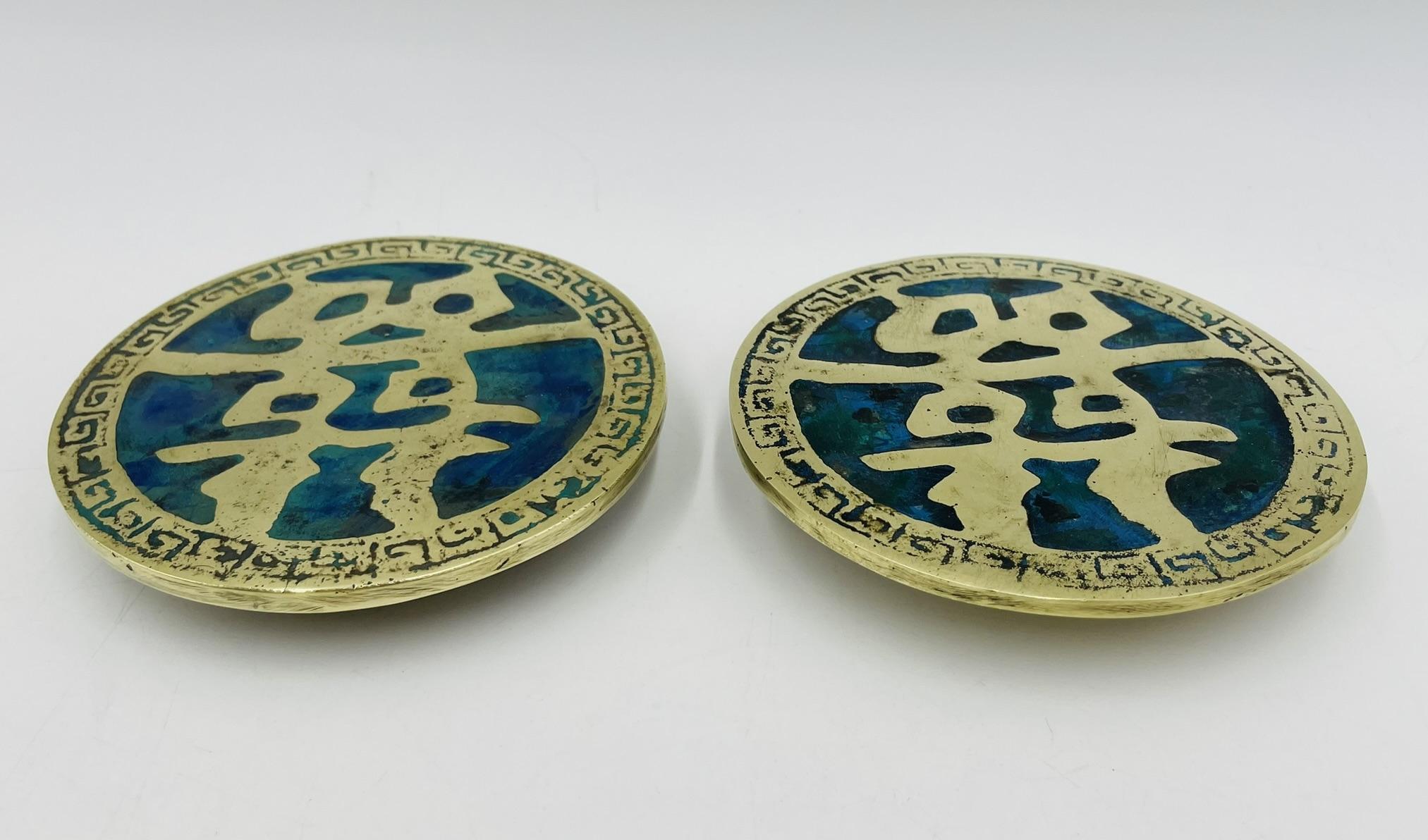 A rare and collectible pair of round brass and enamel door pulls by acclaimed Mexican designer Pepe Mendoza, created in 1958. These sculptural hardware elements feature stylized Chinese characters in relief, surrounded by a decorative border with