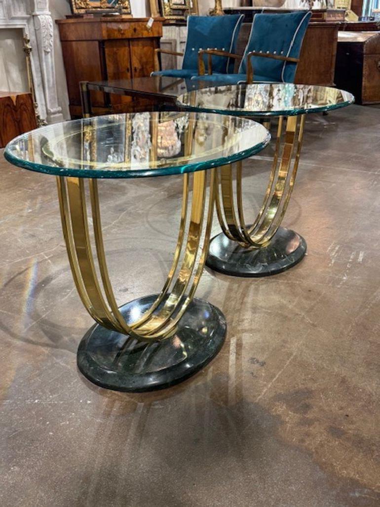 Questo prodotto è una coppia di tavolini vintage Art Déco in ottone e vetro, dal design elegante e classico. Questi tavoli trasudano  un fascino sofisticato, perfetto per aggiungere un tocco di eleganza vintage a qualsiasi spazio abitativo. Circa