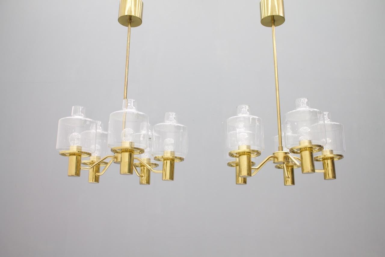 Hans Arne Jakobsson Brass and Glass Chandelier, Sweden, 1960s.
Five clear glasses per item, five Edison bulbs (E27 socket) with maximum 75 watts per bulb, or LED Bulbs
One replacement glass per lamp is include. 

Very good condition with nice