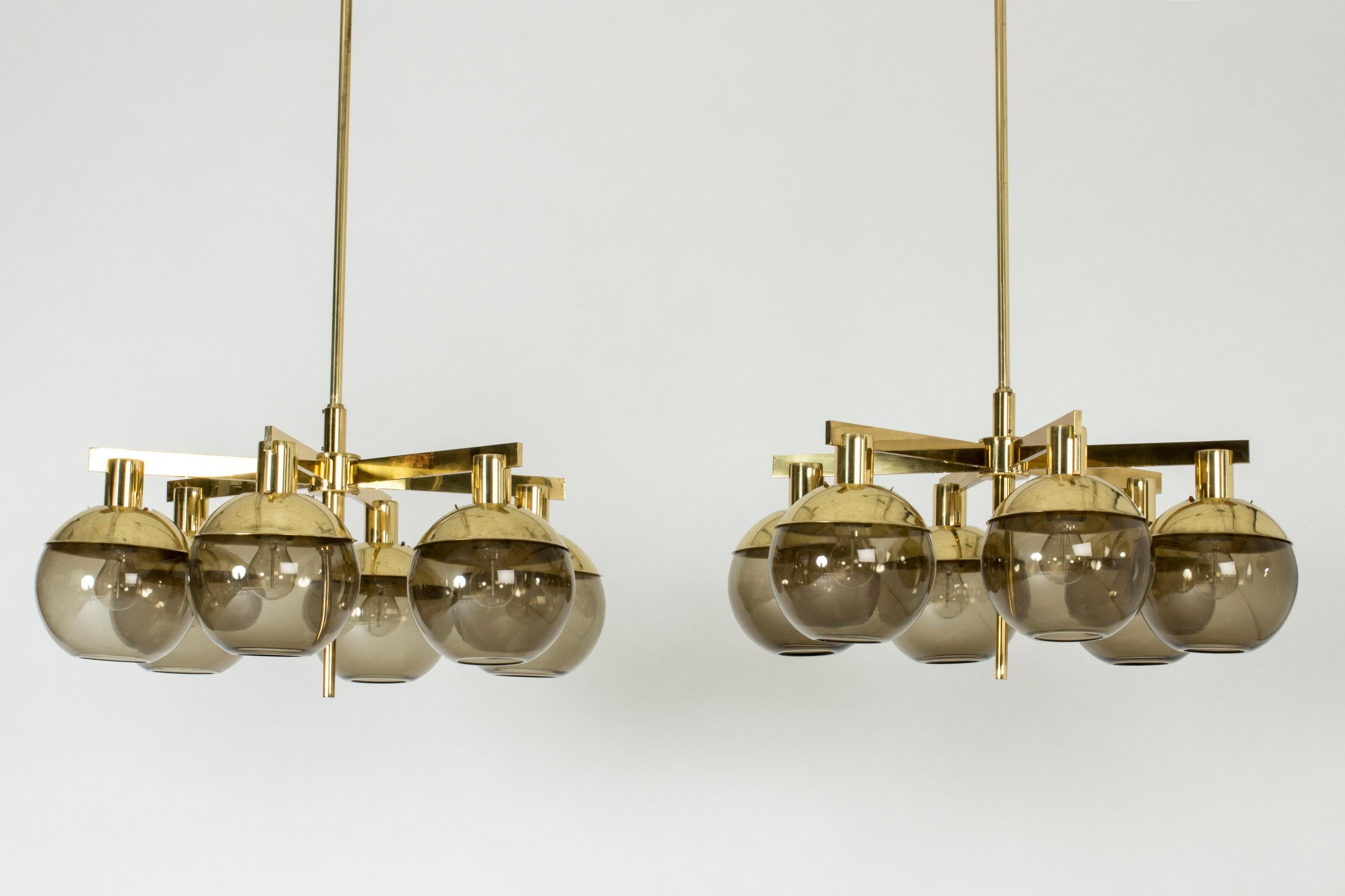 Pair of striking chandeliers by Hans-Agne Jakobsson. Brass frames, each with six arms suspending smoke colored glass shades.