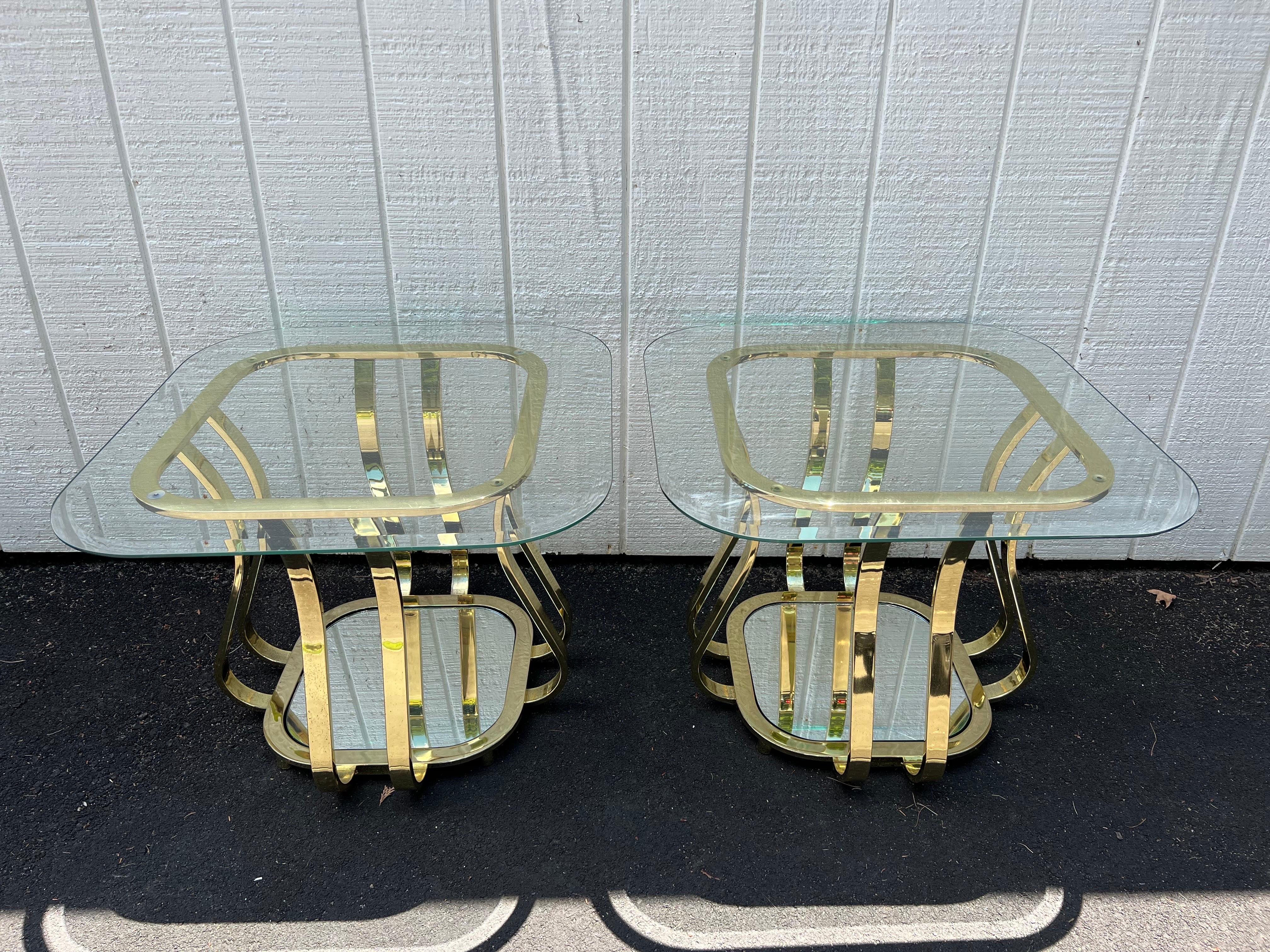 Pair of Hollywood Regency Brass and Glass end tables with mirrored bottom shelves. Art deco 1980's post modern style. These beauties will bring high glamour to any room.
