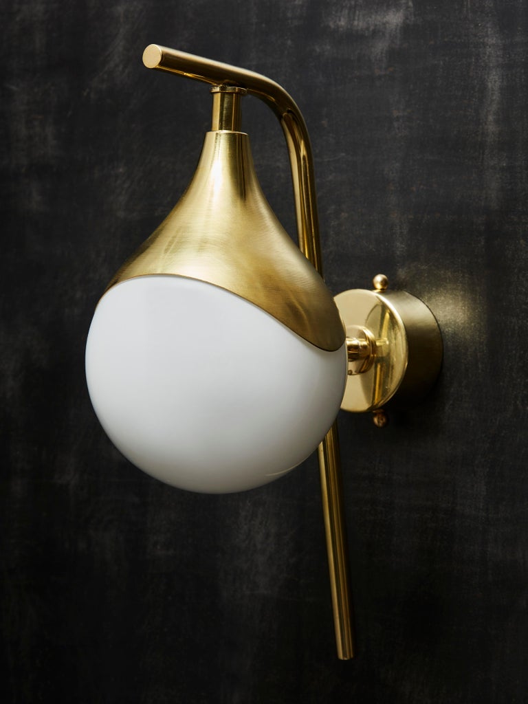 Pair of wall sconces each made of a brass L shaped arm from which hang an enlightened white glass globe.



Price displayed for a pair.