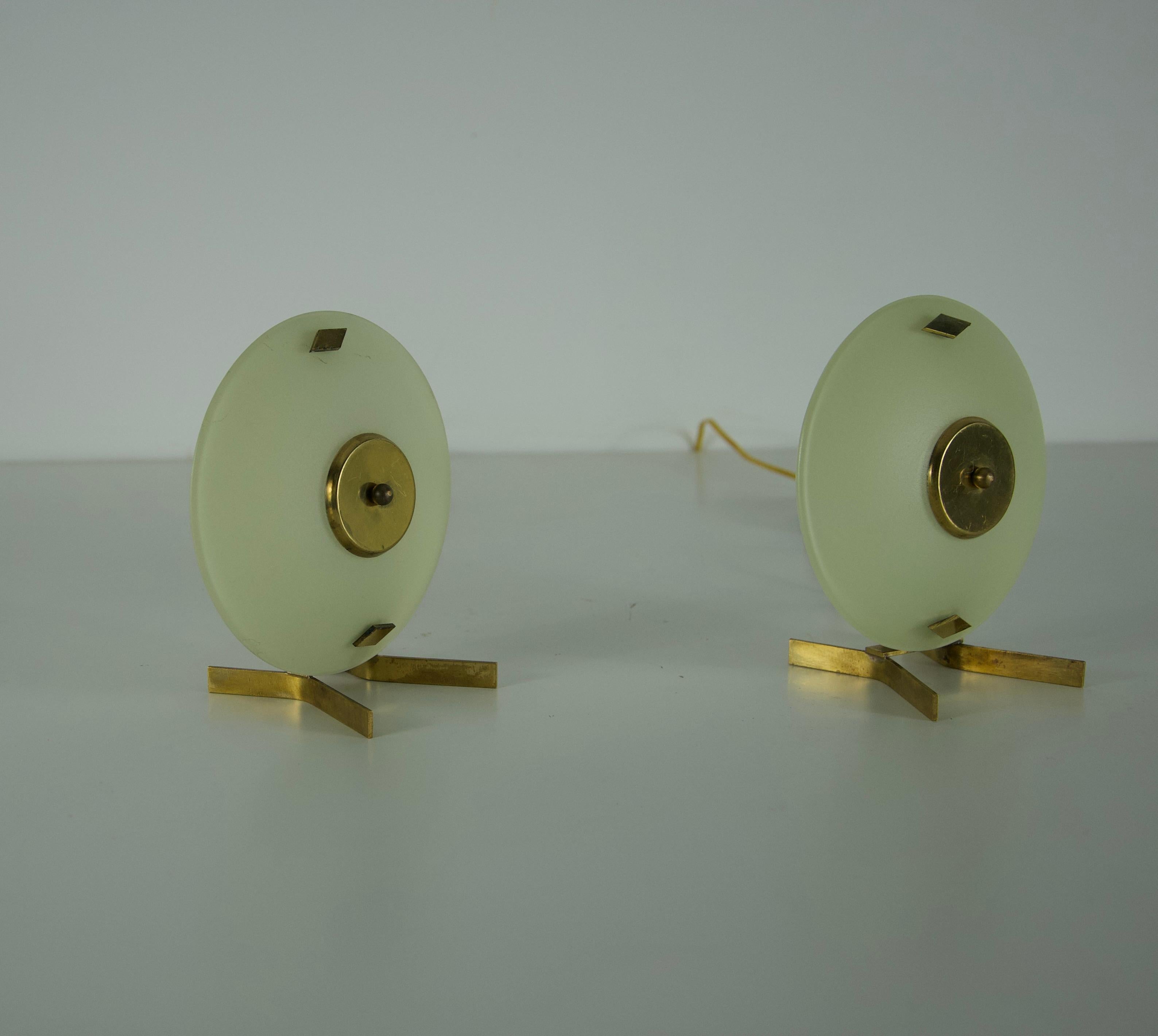 Cette élégante paire de lampes de table en laiton et verre d'Italie, datant des années 1950, met en valeur l'esthétique raffinée du design moderne du milieu du siècle dernier. Chaque lampe présente un diffuseur circulaire en verre dépoli maintenu