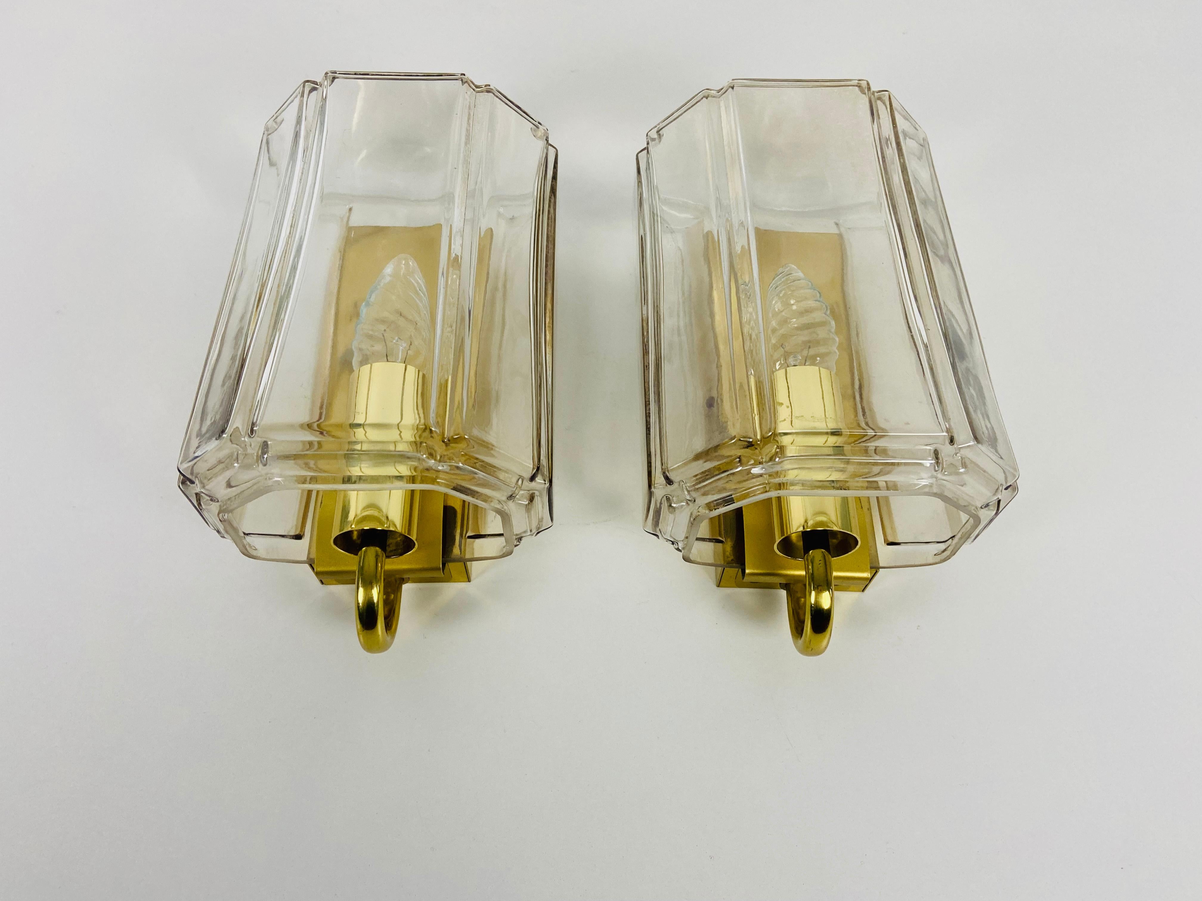 A beautiful pair of glass wall lamps made by Glashütte Limburg in Germany in the 1970s. The light is made of thick glass. It has an amazing transparent color and it is very solid. The body is made of solid brass.

The lights require E14 light
