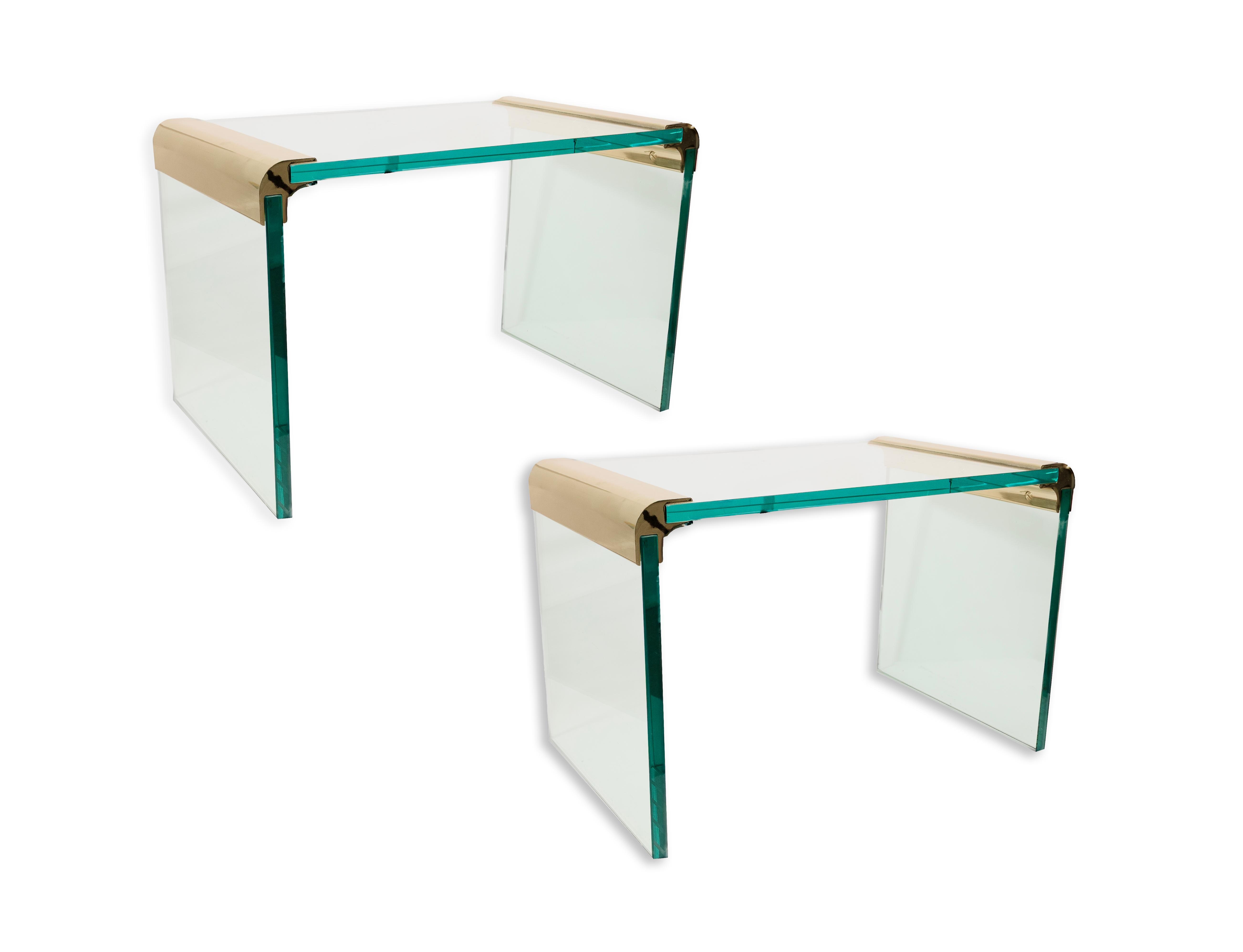 This is a pair of brass and glass end tables designed by Leon Rosen for Pace. The tables feature a stunning flowing design that resembles a waterfall, enhanced by the blue-tinted glass. The brass corners have softly rounded edges, adding to the