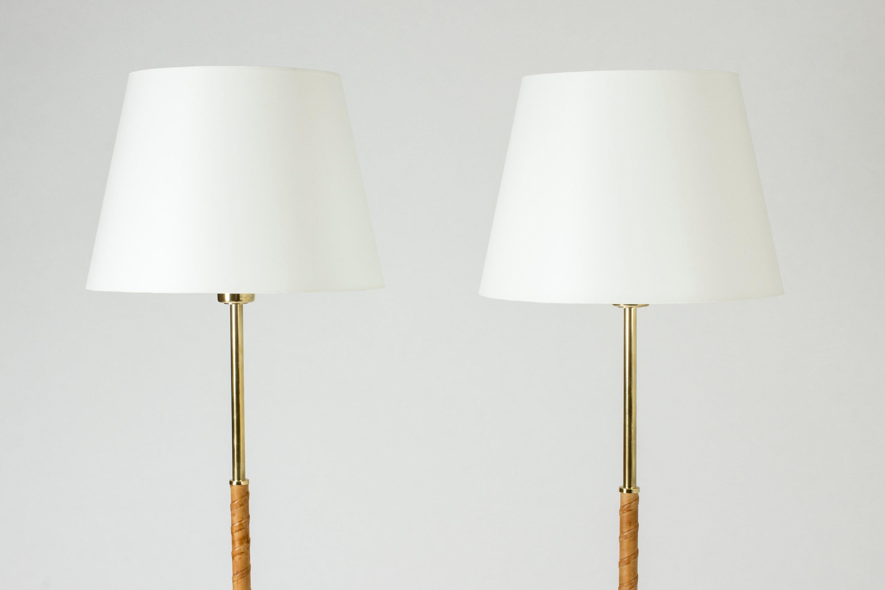 Pair of elegant brass floor lamps from Böhlmarks. Made from brass with natural leather wound handles, smooth brass bases.