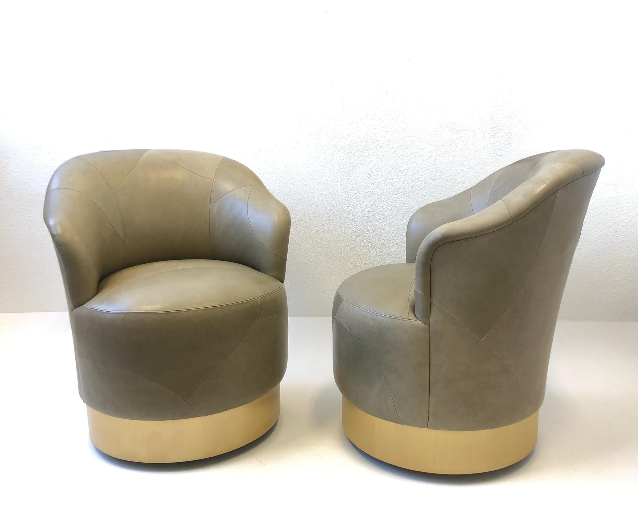 Beautiful pair of patchwork leather chairs with a brushed brass base designed by Sally Sirkin Lewis for J. Robert Scott in the 1980’s. Original dark khaki distressed leather. 
They show minor wear consistent with age. The chairs swivel and are on