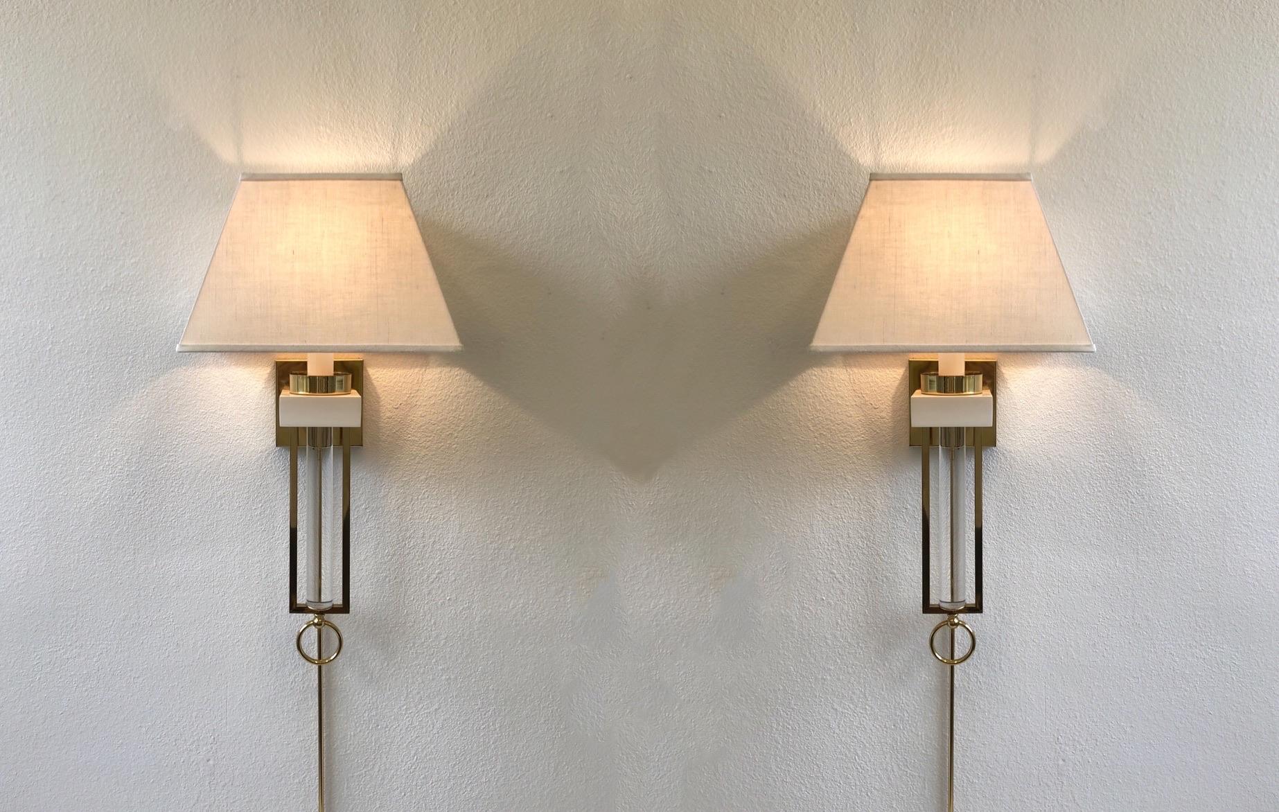 Glamorous 1970s pair of ‘Regency’ wall sconces.
The sconces are constructed of polish brass, clear Lucite, white lacquered wood with vanilla linen shades.
This are in original condition and can be wired directly or with a plug.
Measurements: