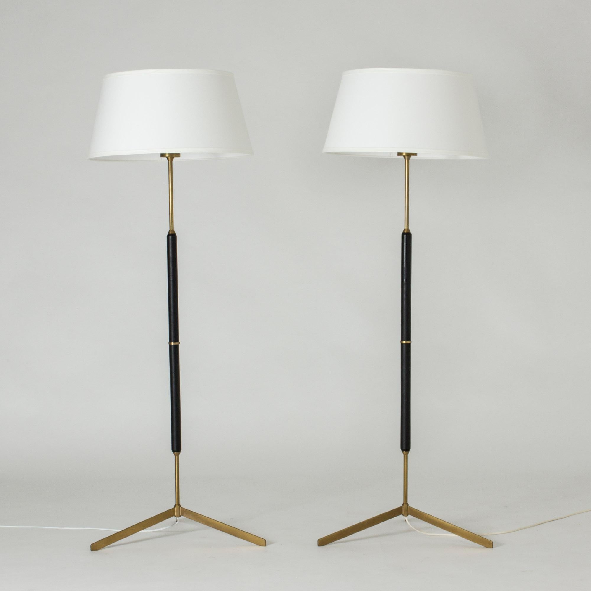 Pair of sleek and cool floor lamps from Bergboms, made from brass and black lacquered wood. Tiltable lamp shades, nice brass hoops around the light bulbs make a decorative detail inside.