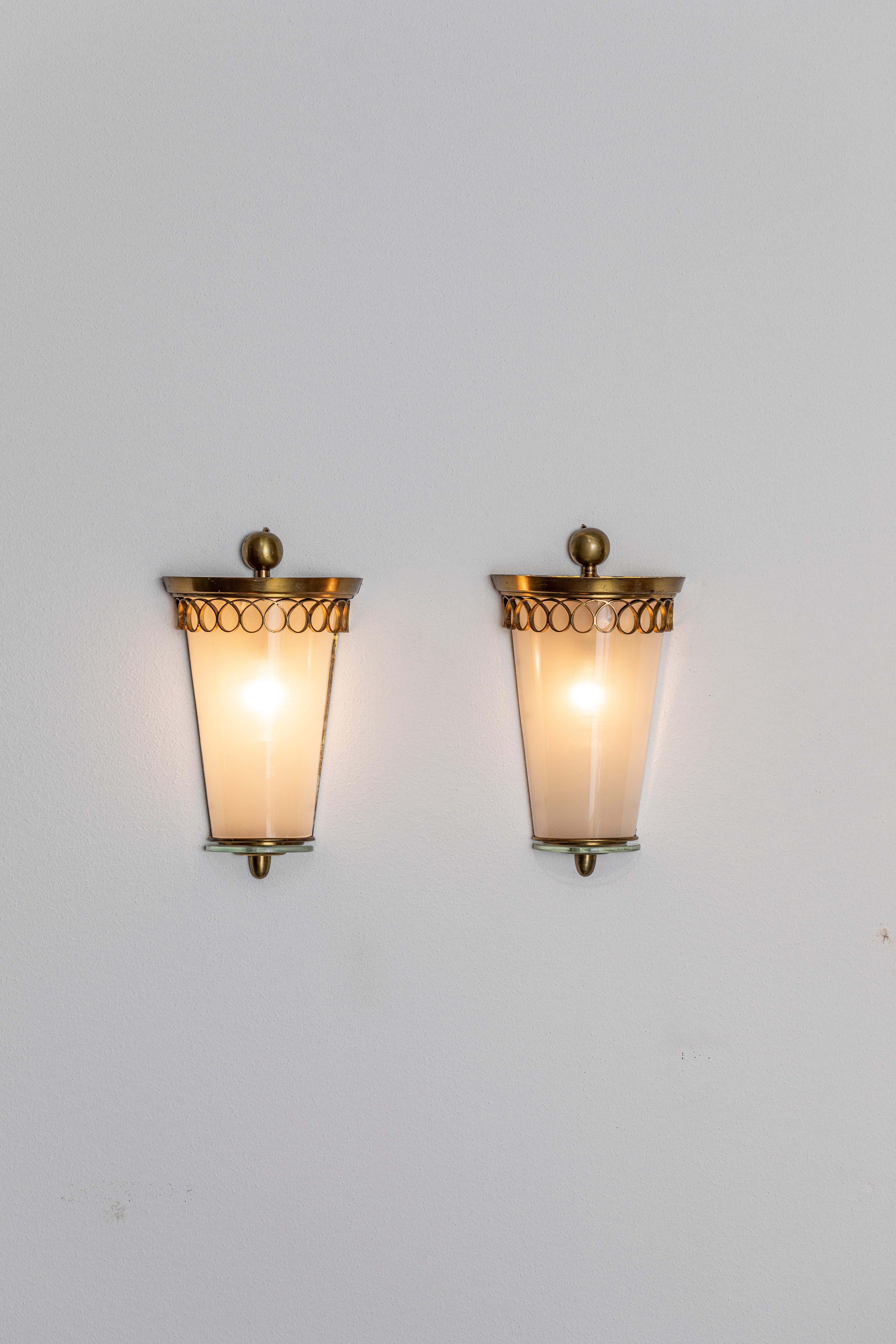 Pair of golden brass and opaline glass sconces, executed in the typical Italian Art Deco style of the 1940s and early 1950s.