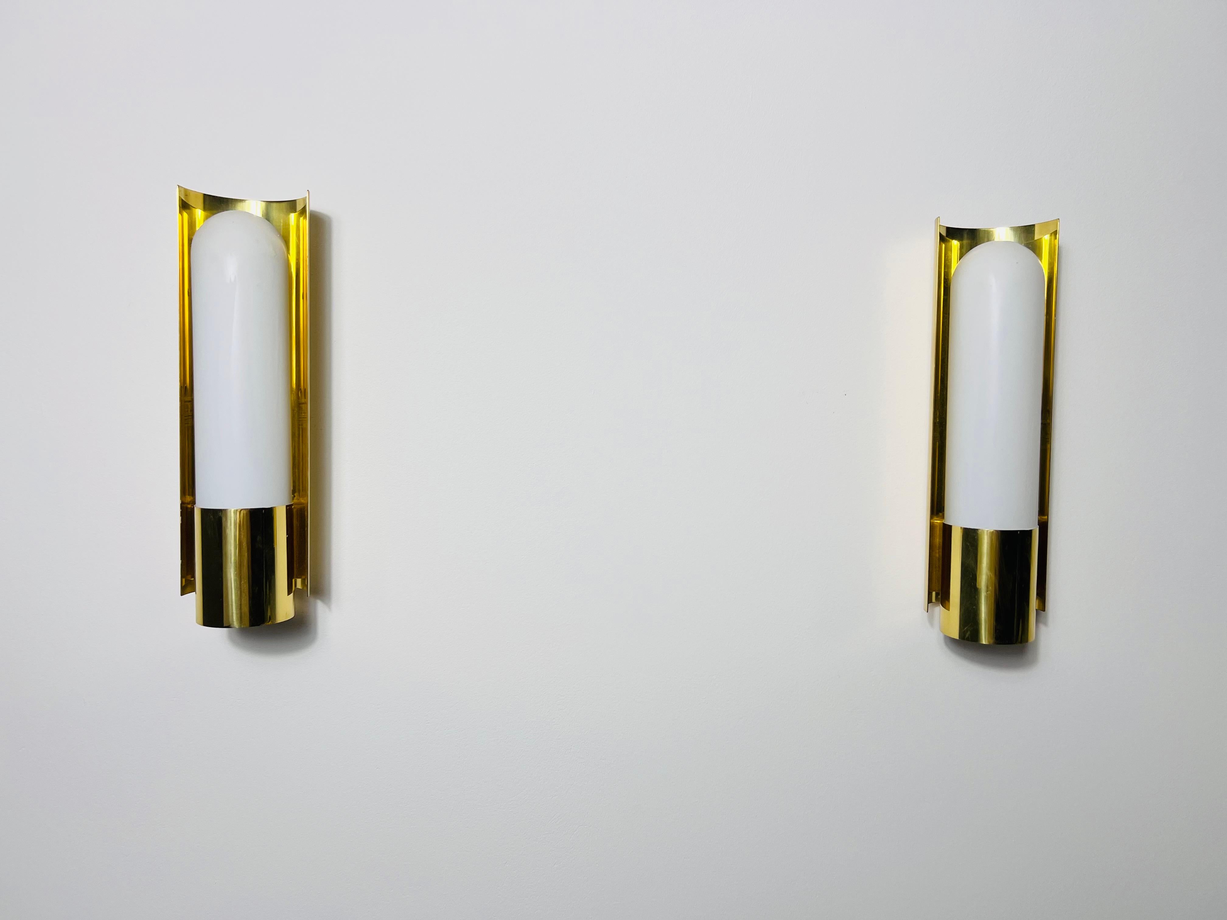 This pair of distinguished Limburg wall lamps, crafted in the 1960s, exemplifies the superior quality and precision of German workmanship. The lamp is elegantly designed with a brass frame that encases a refined opal glass shade, which is securely
