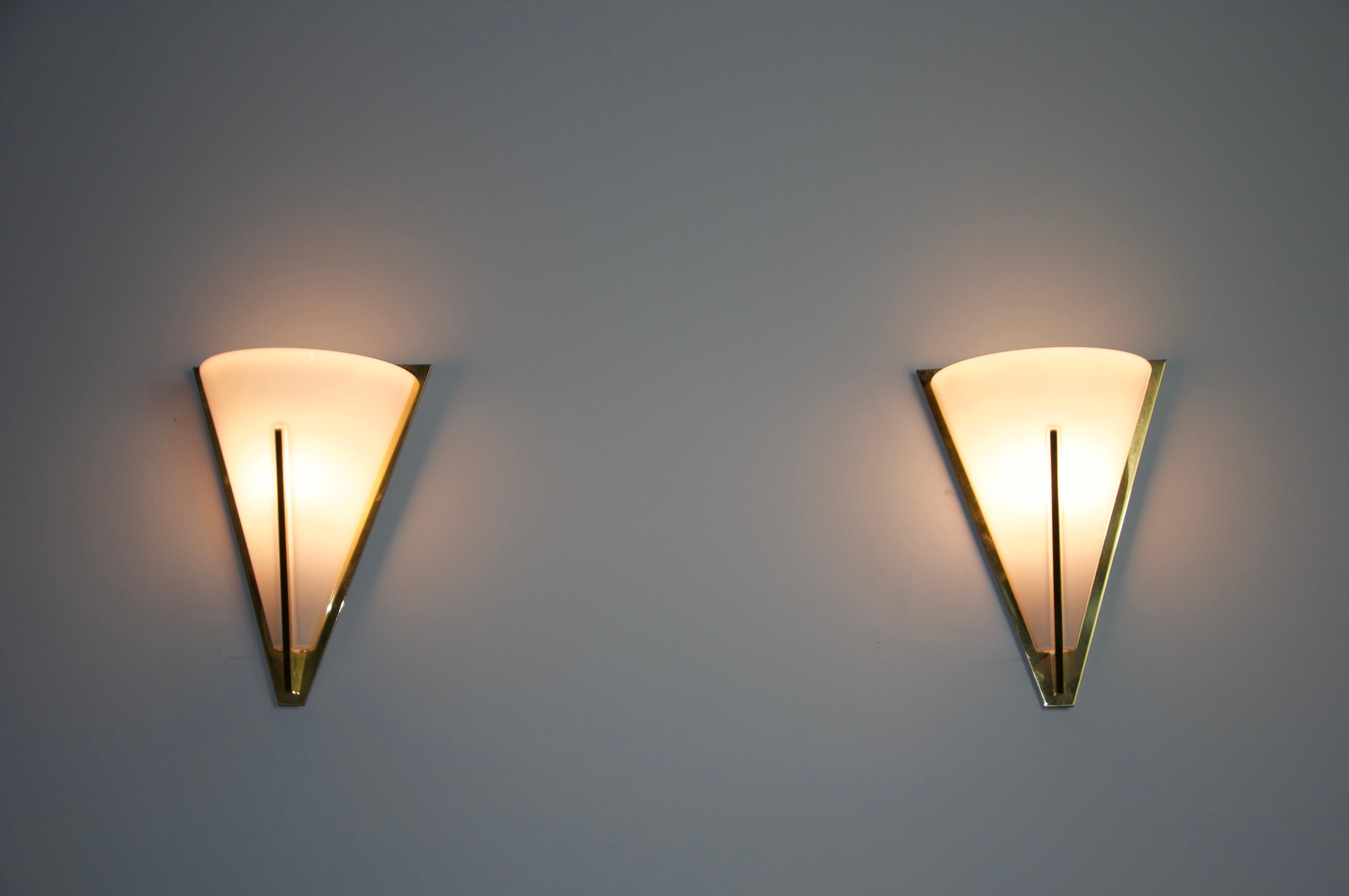 This pair of distinguished Limburg wall lamps, crafted in the 1960s, exemplifies the superior quality and precision of German workmanship. The lamp is elegantly designed with a brass frame that encases a refined opal glass shade, which is securely