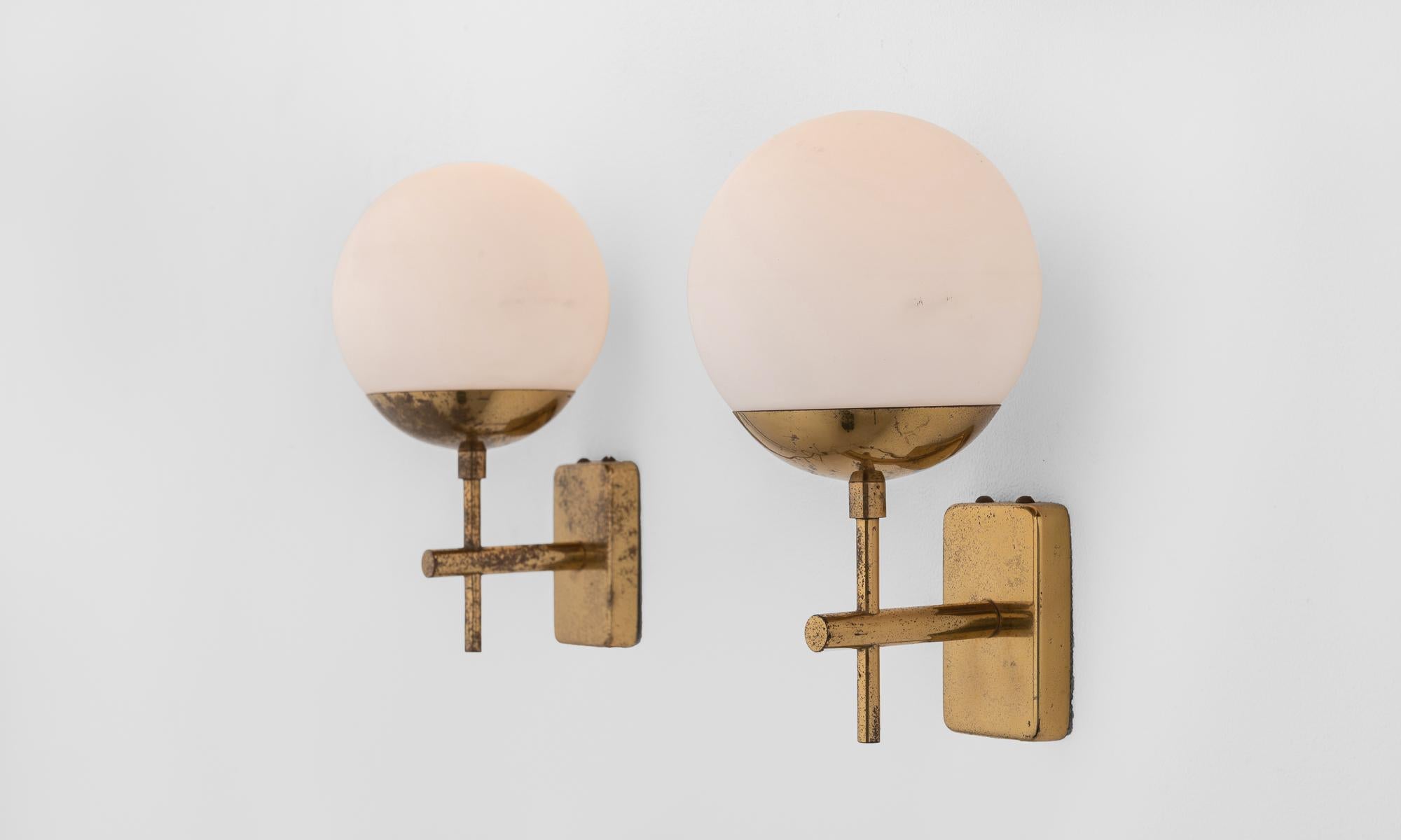Pair of brass and opaline globe sconces, Italy, circa 1960.

Beautifully patinated brass hardware supports a pair of frosted glass shades.