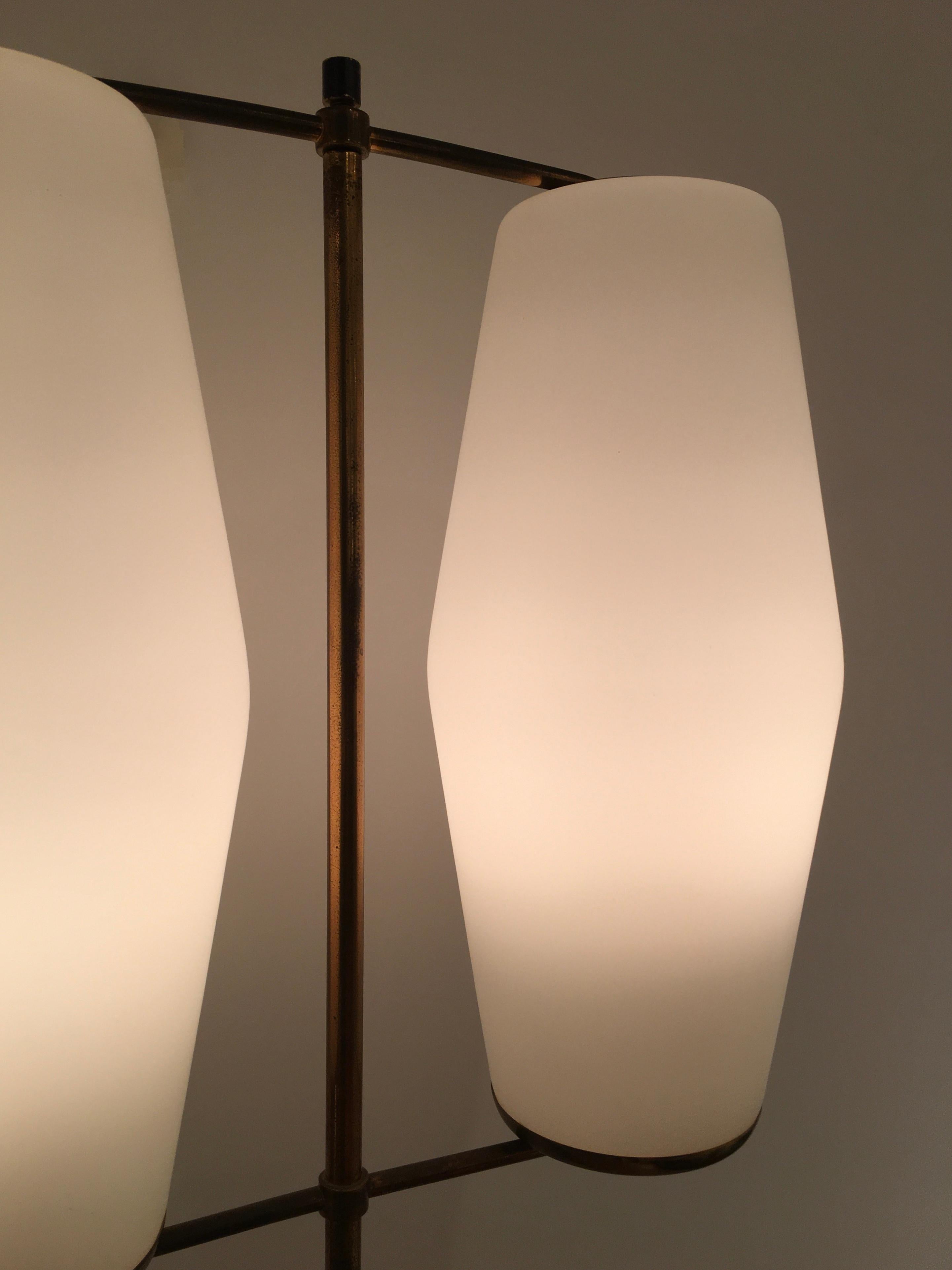 A rare pair of 1950s floor lamps designed and manufactured by Bruno Gatta's innovative lighting company, Stilnovo. Each floor lamp comprises of two opaline glass shades which are held within a double cross-frame made of brass. This is supported by a