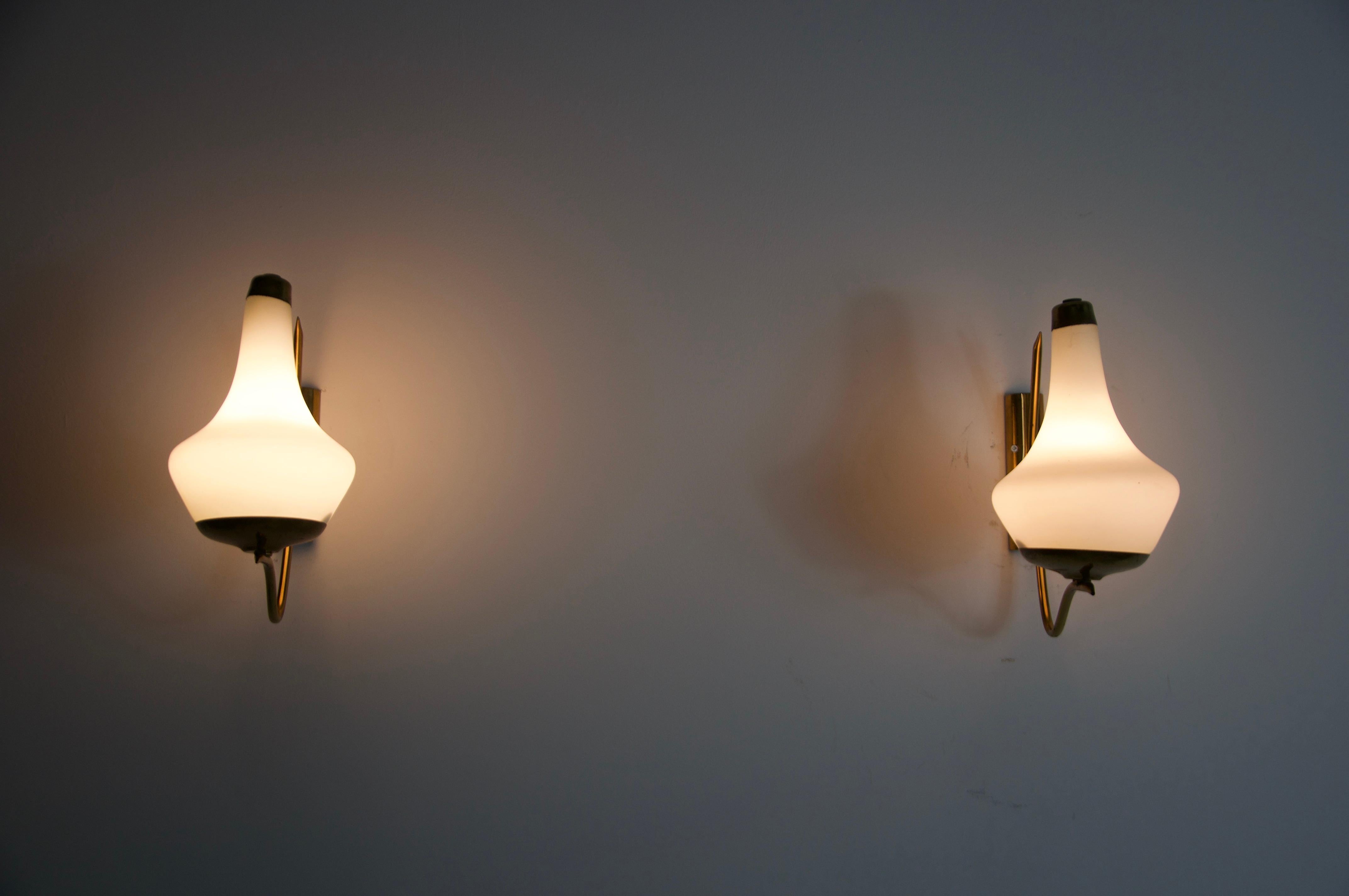 Cette exquise paire d'appliques des années 1960 en provenance d'Italie incarne l'élégance et le savoir-faire du design moderne du milieu du siècle dernier. Conçues et fabriquées par la célèbre marque italienne Stilnovo, ces lampes sont des