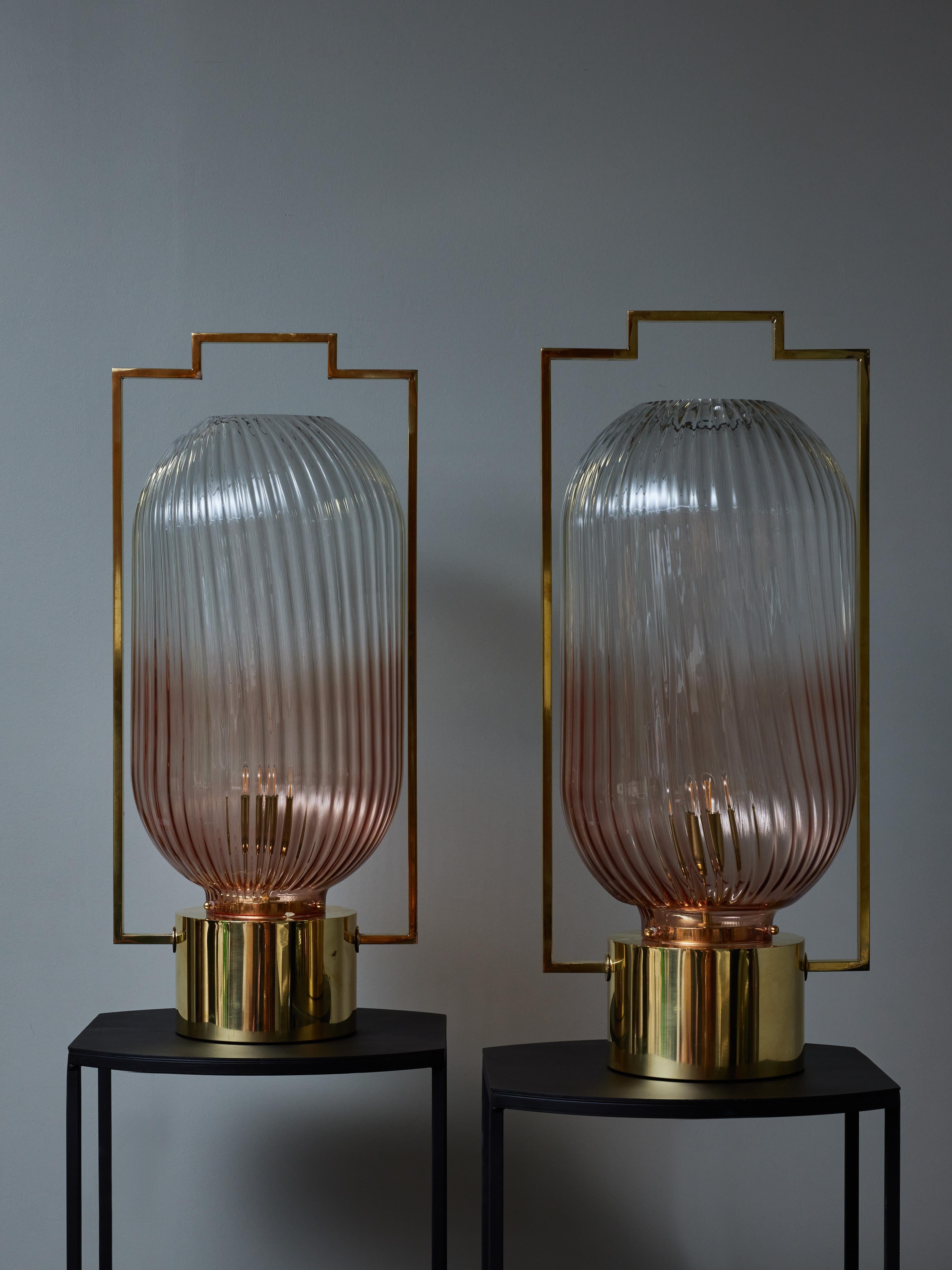 Pair of table lamps made of a brass structure with a central tall fluted Murano glass shade lightly tinted in pink.