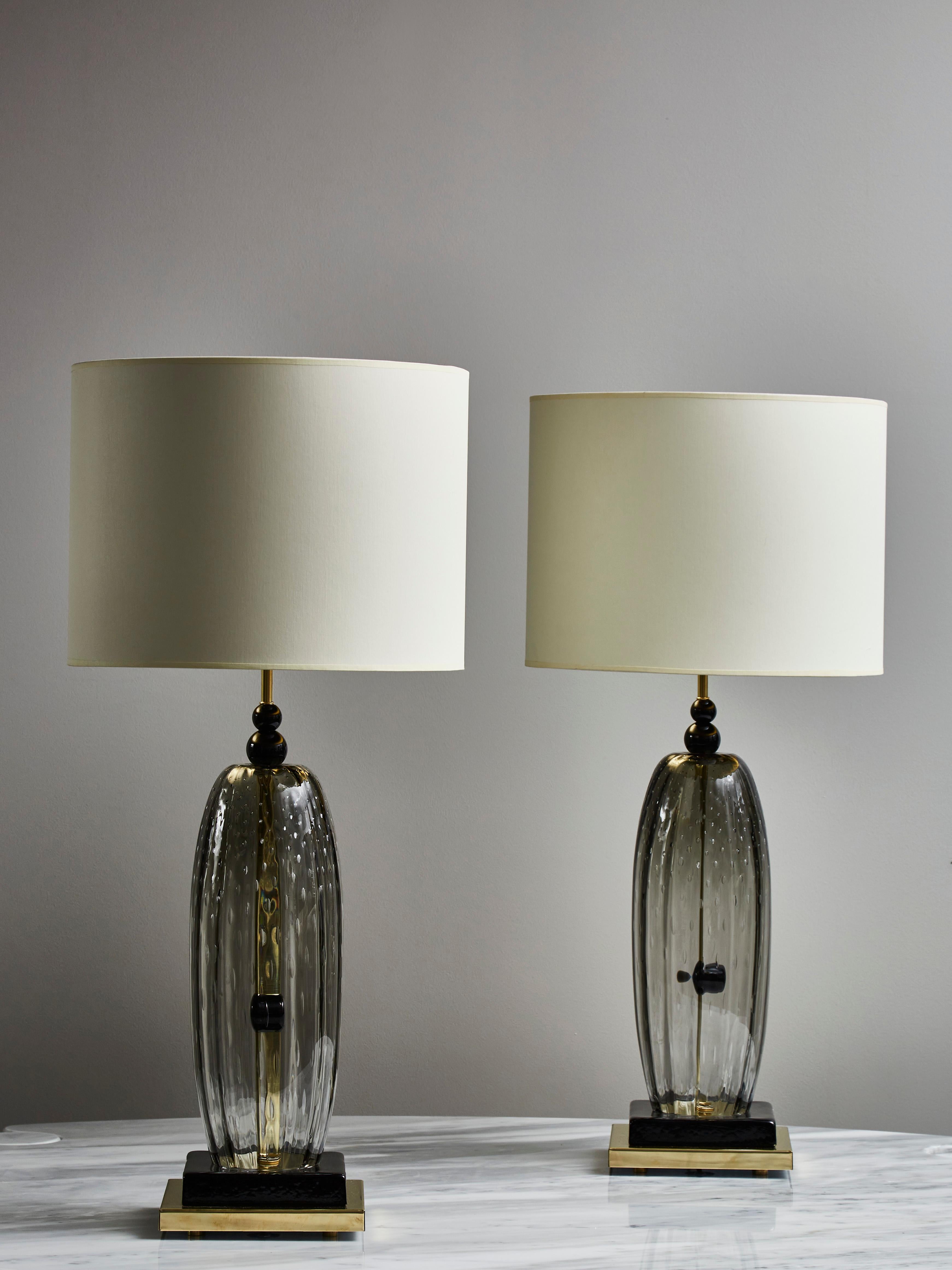 Pair of table lamps made of brass feet and smoked Murano glass body with black tinted Murano glass parts.


Dimensions displayed without the shades.
   