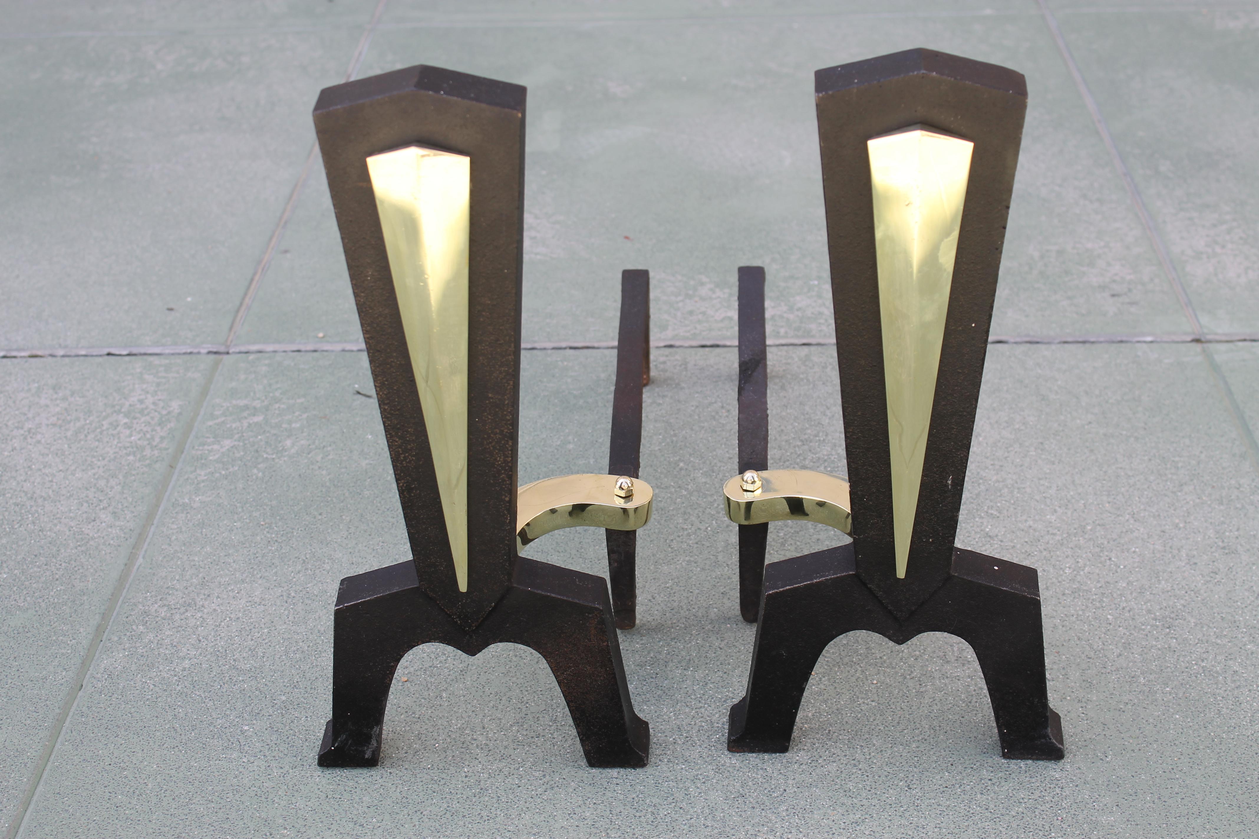 Pair of midcentury fireplace andirons. We're reasonable sure they were designed by Donald Deskey. Brass portions have been polished. They measure 7” wide 17.5” deep and 16” high.