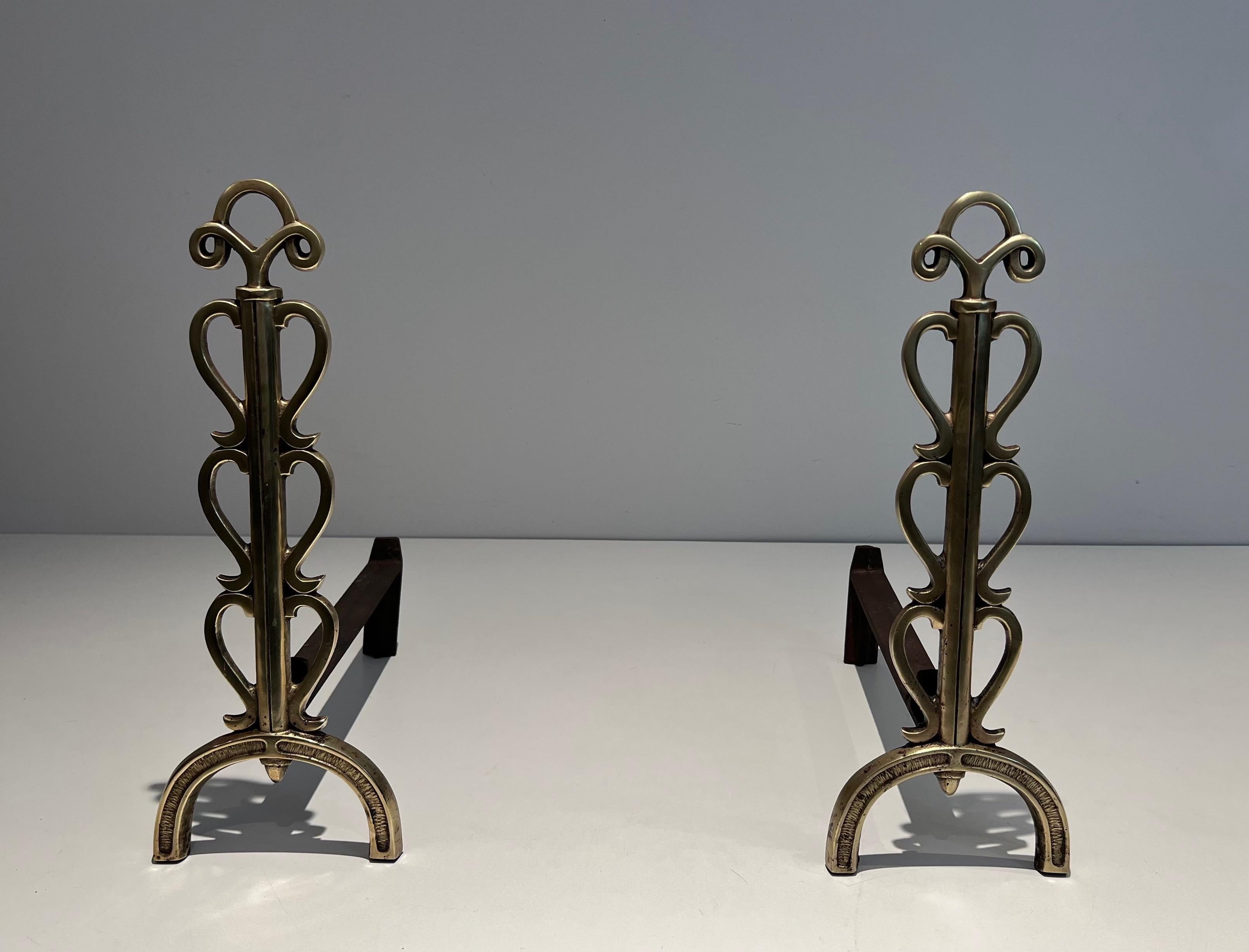 This pair of andirons is made of brass and wrought iron. This is a French work in the style of famous French designer Raymond Subes. Circa 1940.