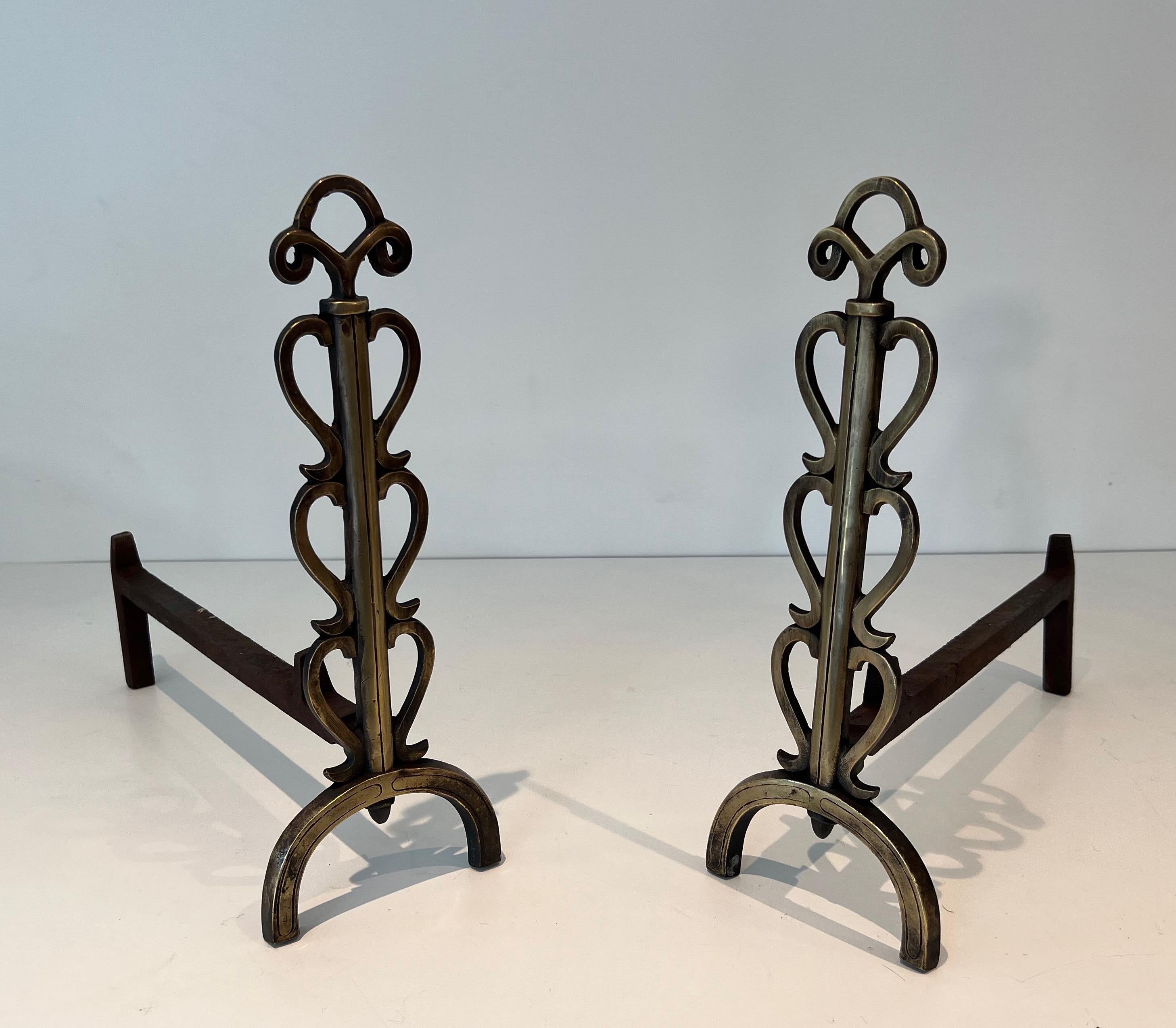 This interesting pair of design andirons is made of brass and wrought iron. This is a French work in the style of famous designer Raymond. Subes. Circa 1970