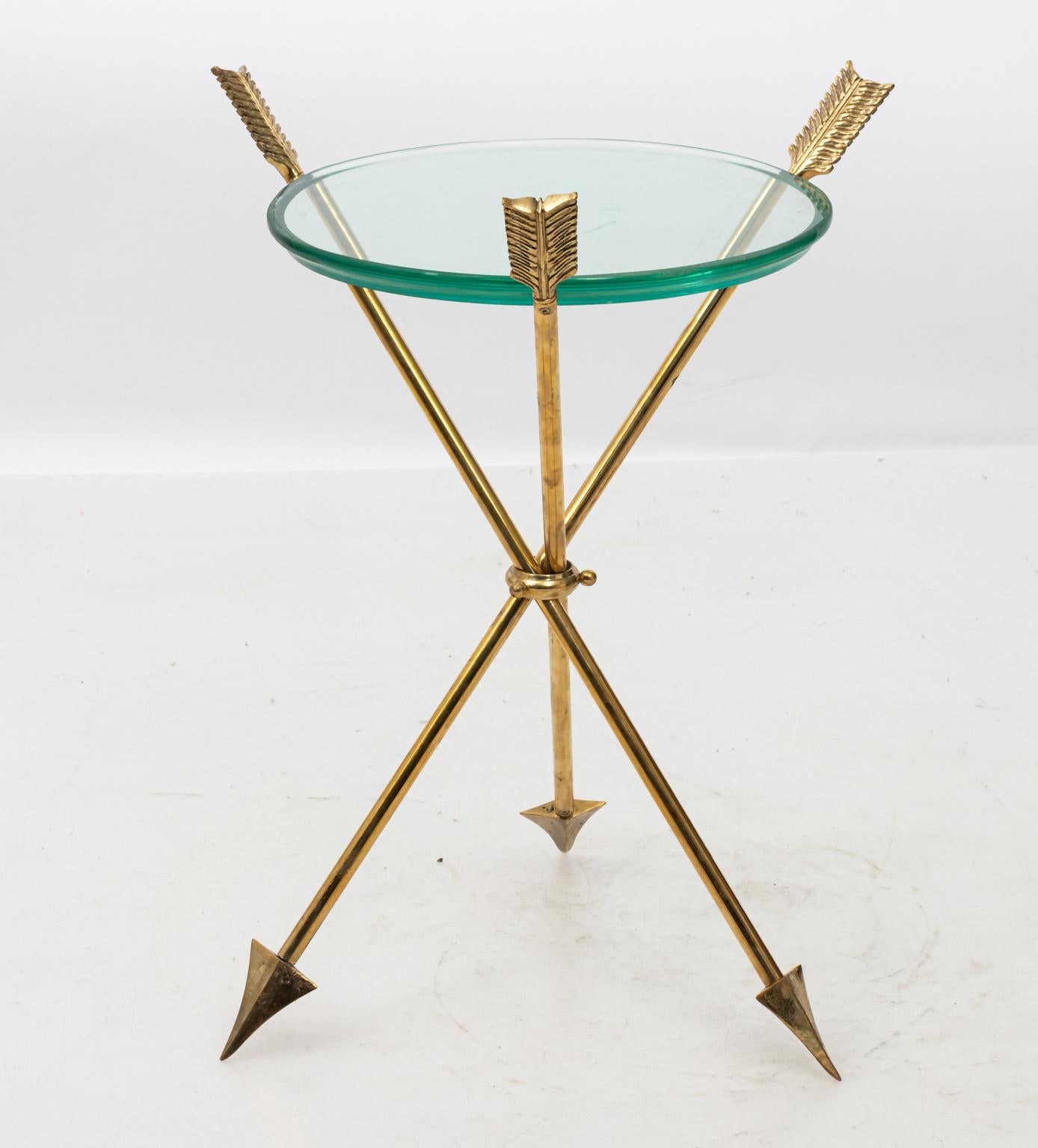 Pair of round, glass top tables supported by brass arrows at the base. Please note of wear consistent with age including minor finish loss along with scratches to the removable glass top and brass base.