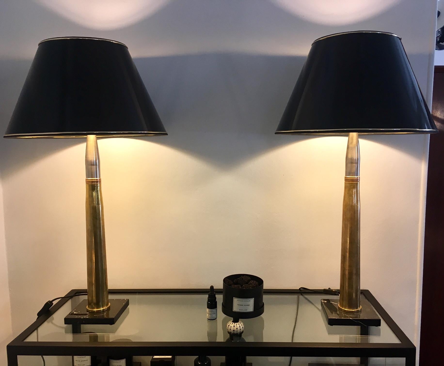 Paire de grandes lampes de table avec abat-jour laqué noir et tige en métal et douille d'artillerie en laiton. Base en pierre foncée.