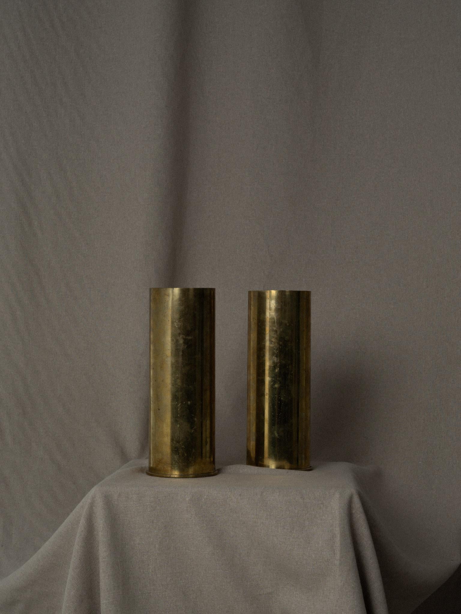 Pair of antique brass artillery shell casings from World War II. Made out of brass, these impressive heavy pieces of artillery are round in shape and dated on the bottom (1944). These memorabilia are in excellent condition with a rich patinated