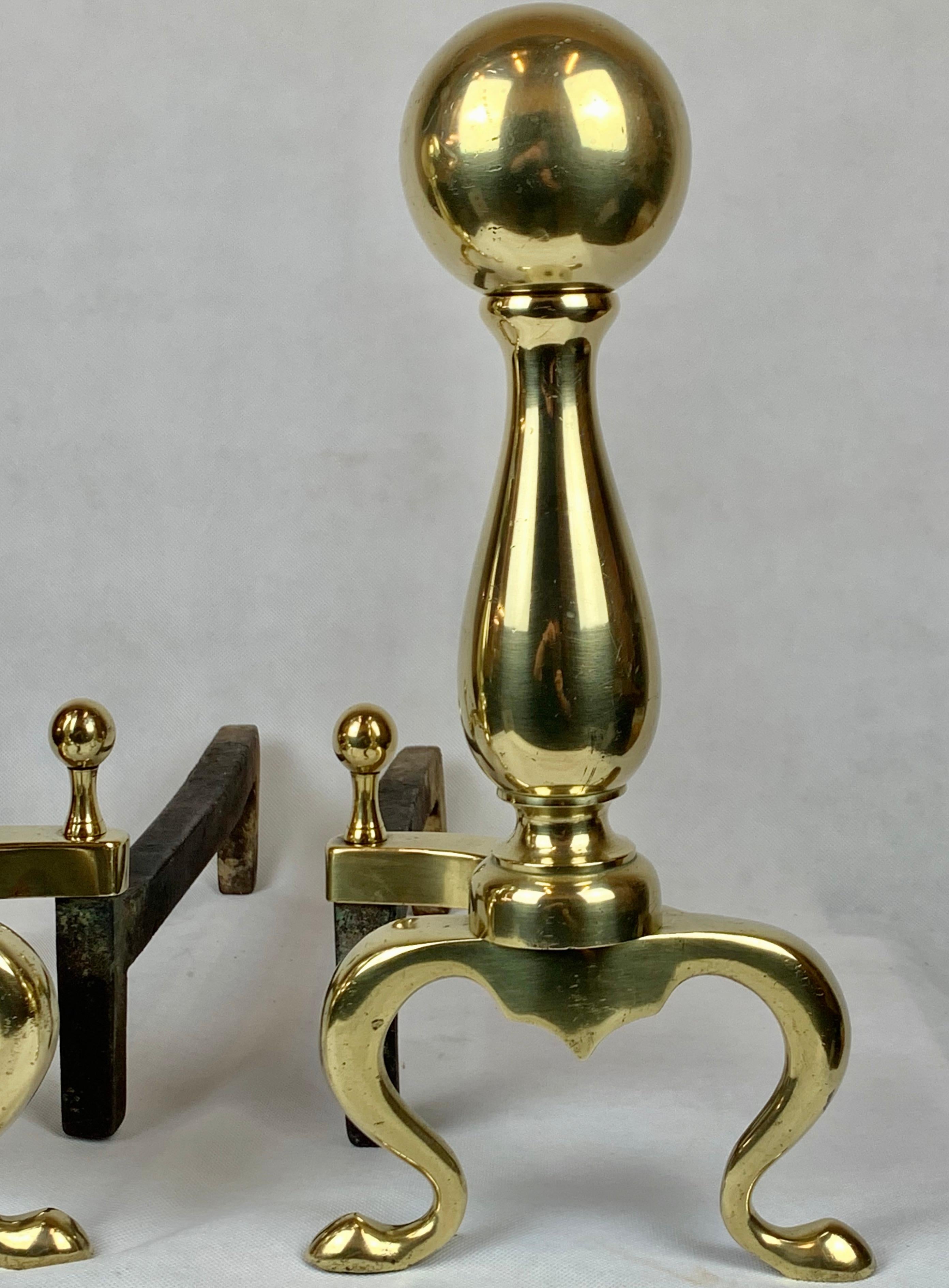 Pair of solid brass ball top andirons. The ball top sits upon a baluster turned column. The column rests upon arched supports with scrolled legs and coin feet. They are in good order with no major dents or cracks to the metal.
Foundry mark on the