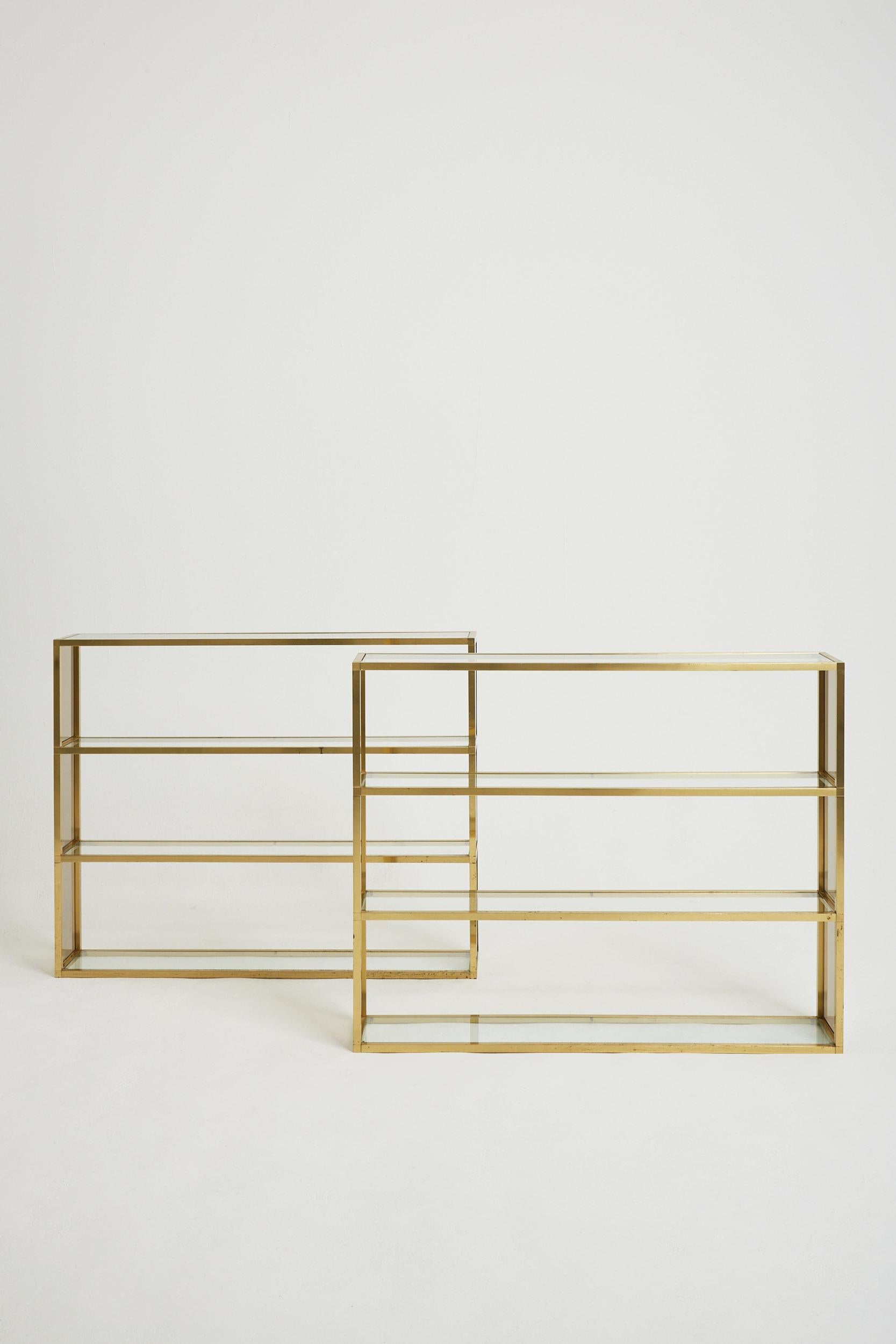 A pair of brass four-tier glass and smoked glass bookcases or étagères.
France, Circa 1970.
 