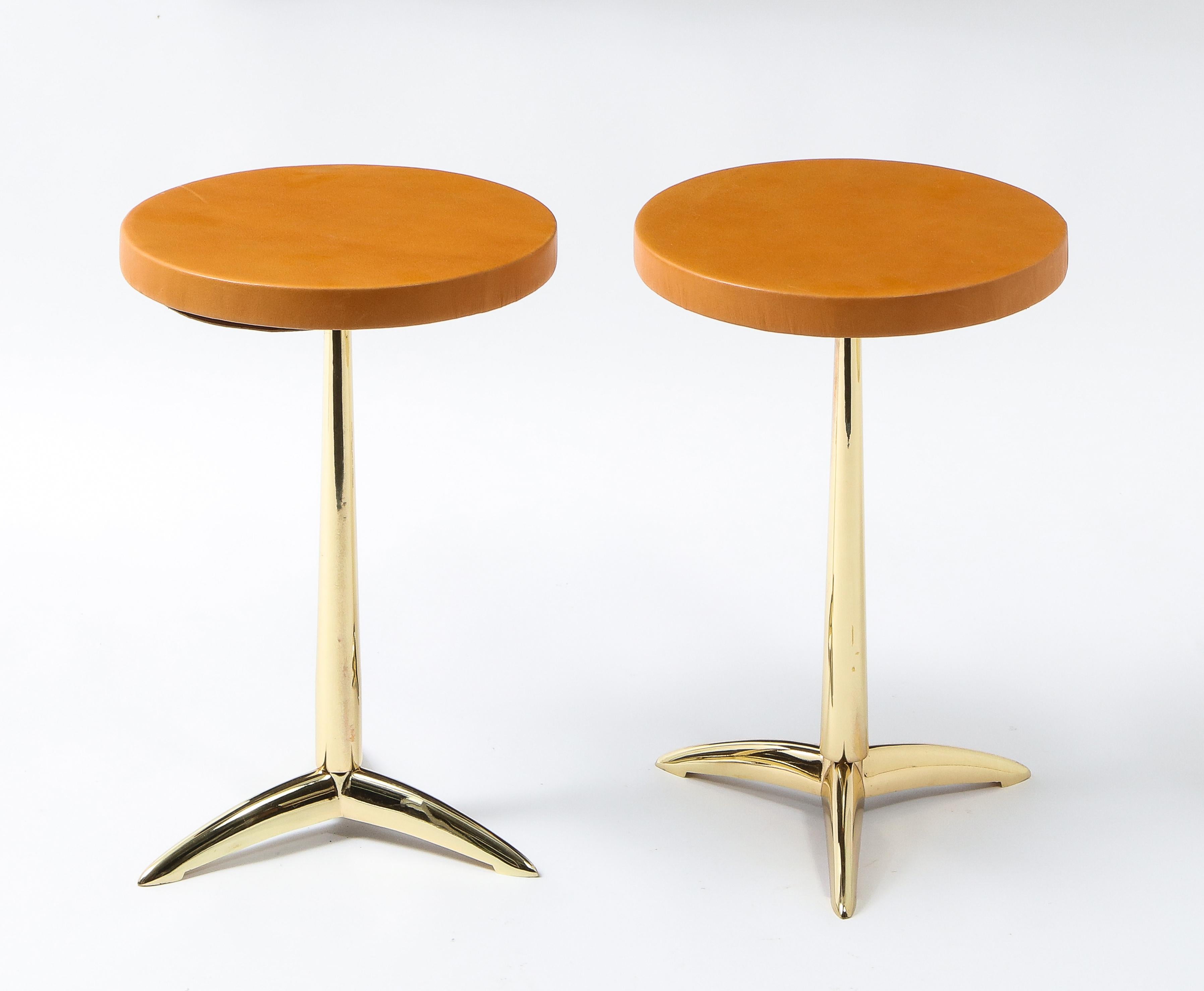 Classic tripod drink stands in brass with leather-covered tops.