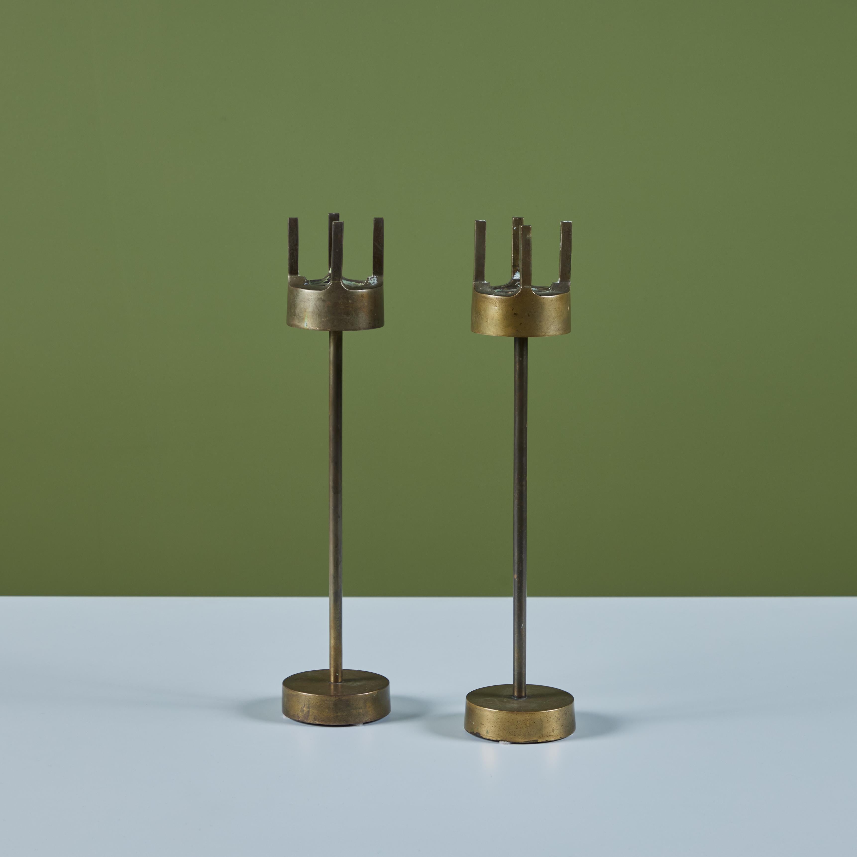 Pair of solid brass candlesticks. The pair of beautifully patinated candlesticks feature thick round bases with narrow stems and the same thick round candle holder with a prong like detail.

Dimensions 
3