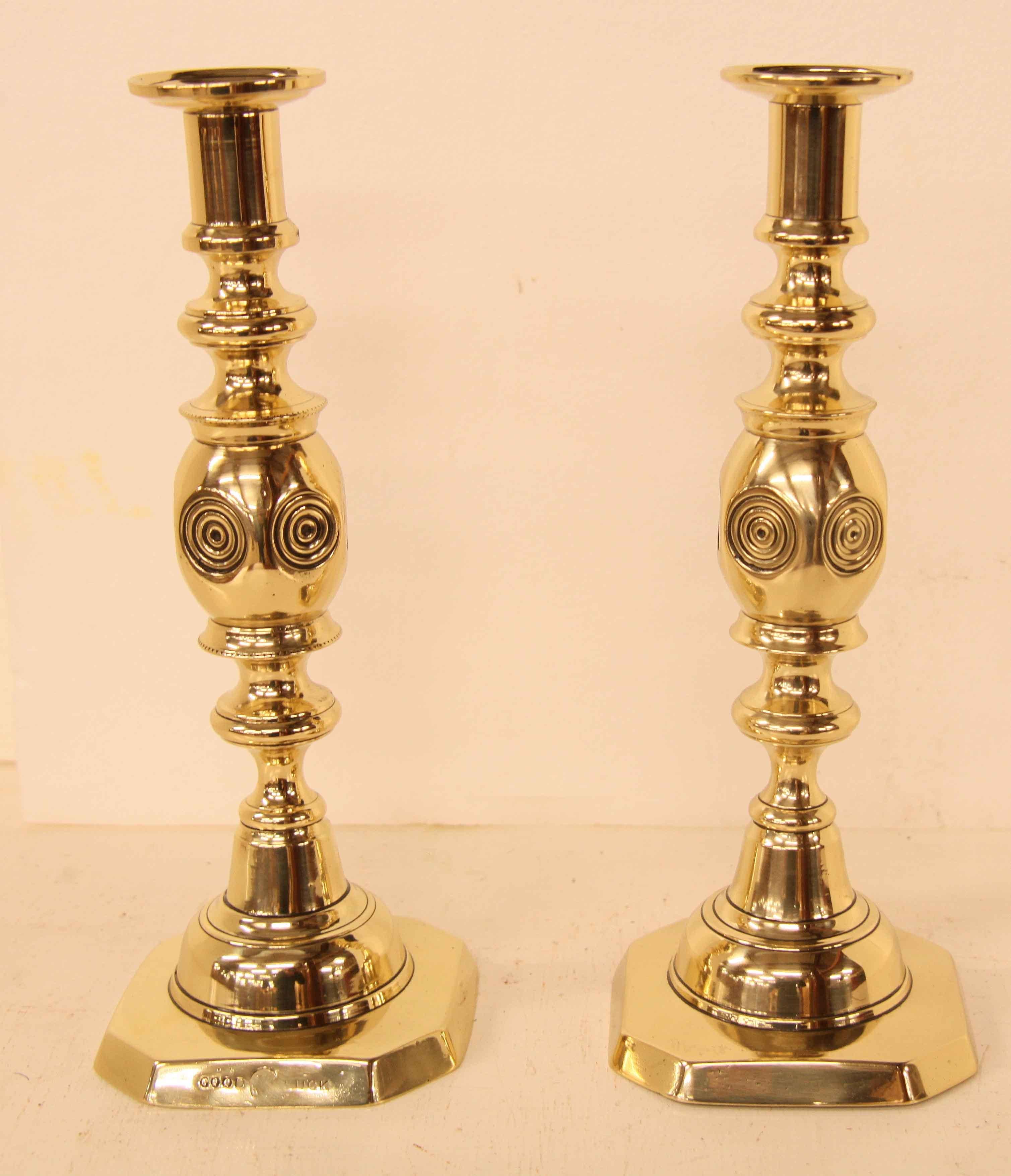 Pair of brass ''bull's eye'' candlesticks,  these English candlesticks are aptly named for the central feature that resembles a bull's eye.  They have the ''GOOD LUCK'' mark at the bottom in honor of Queen Victoria's jubilee;  they retain their push