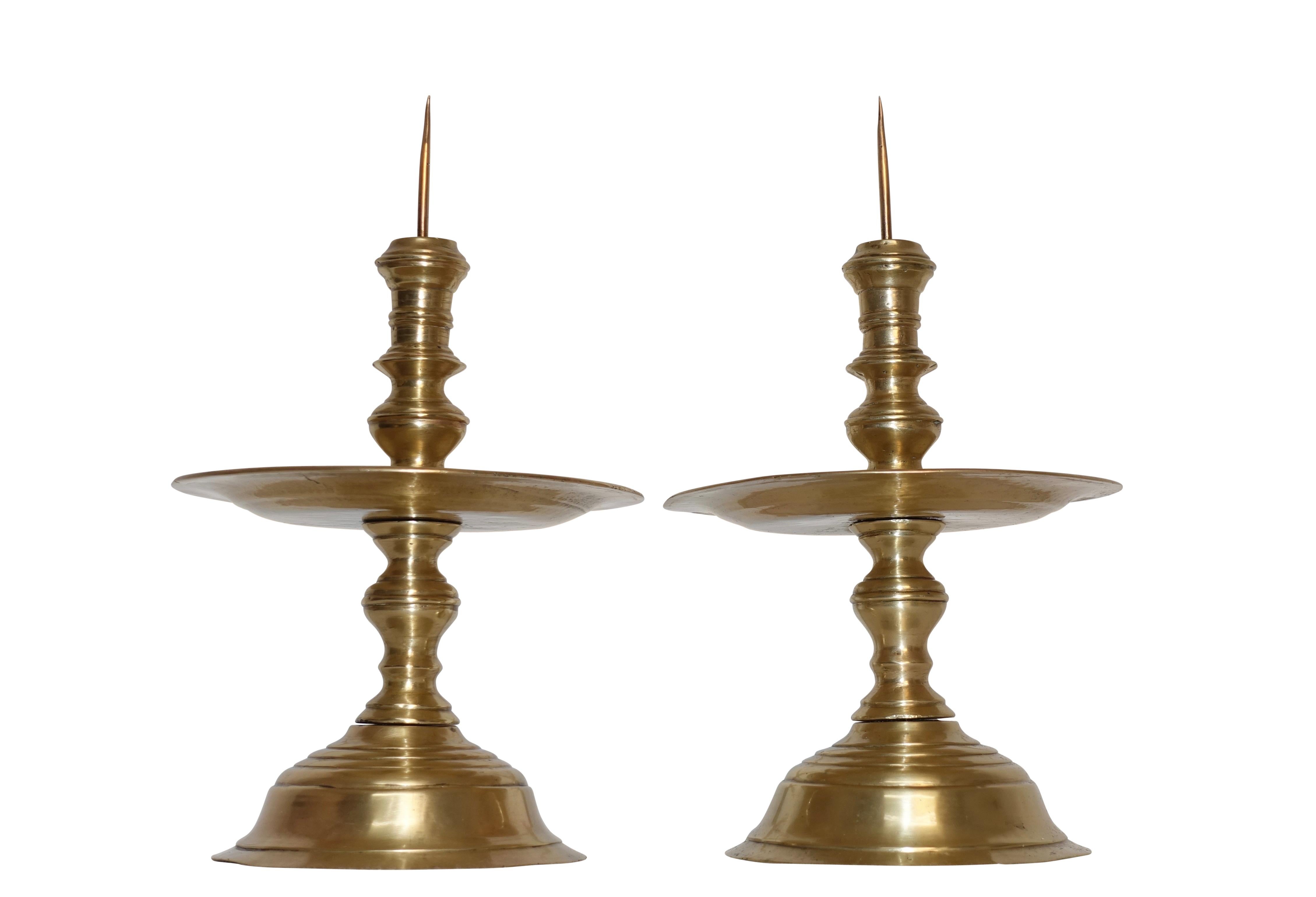 A magnificent pair of early hand spun brass pricket candleholders with turned baluster shape centre column above and below the exaggerated drip plates, Dutch, circa 1750.