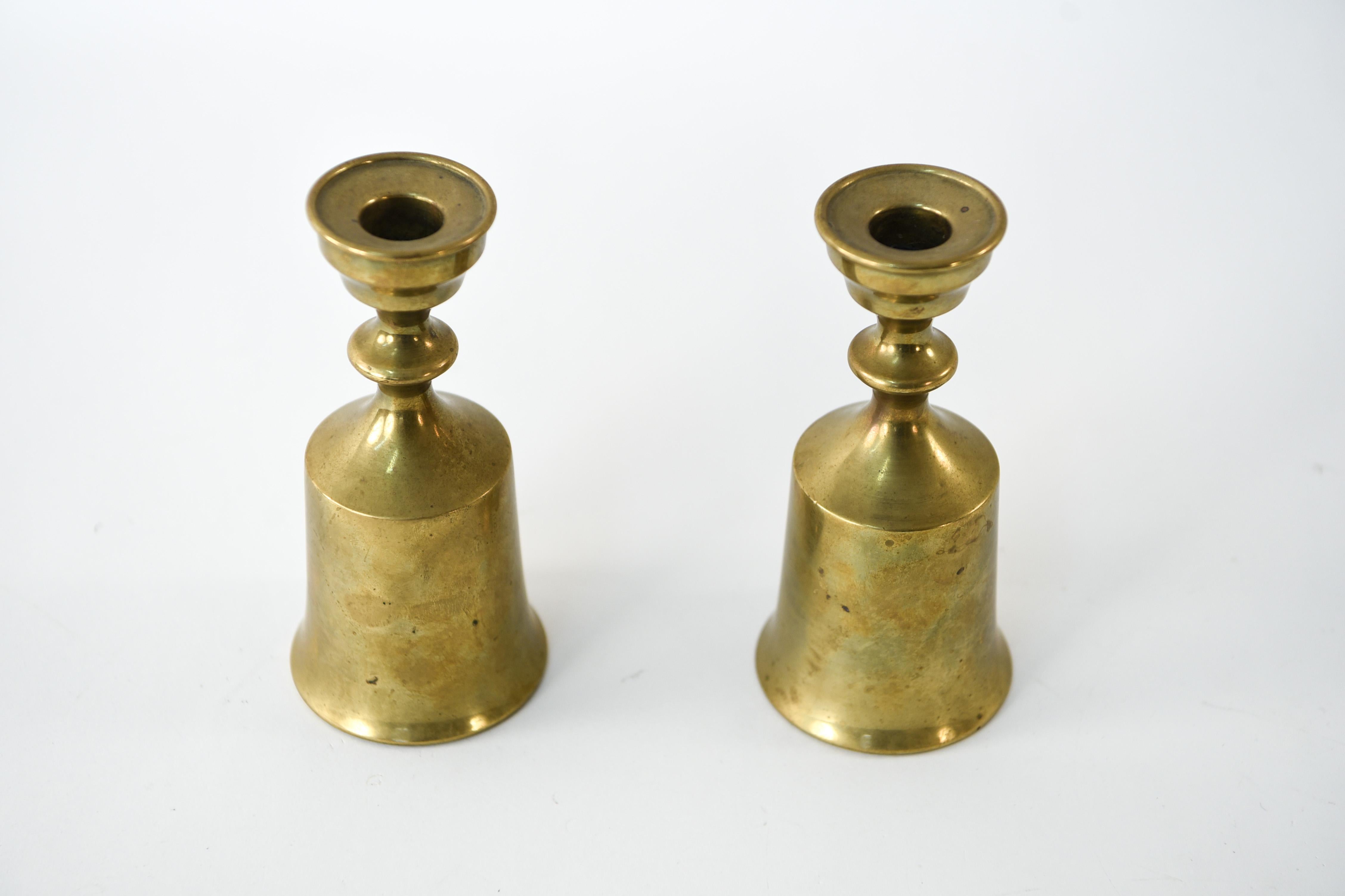 This is a pair of turned brass candlesticks designed by Jens H. Quistgaard for Dansk. These candlesticks from the 1950s have a modern flair.