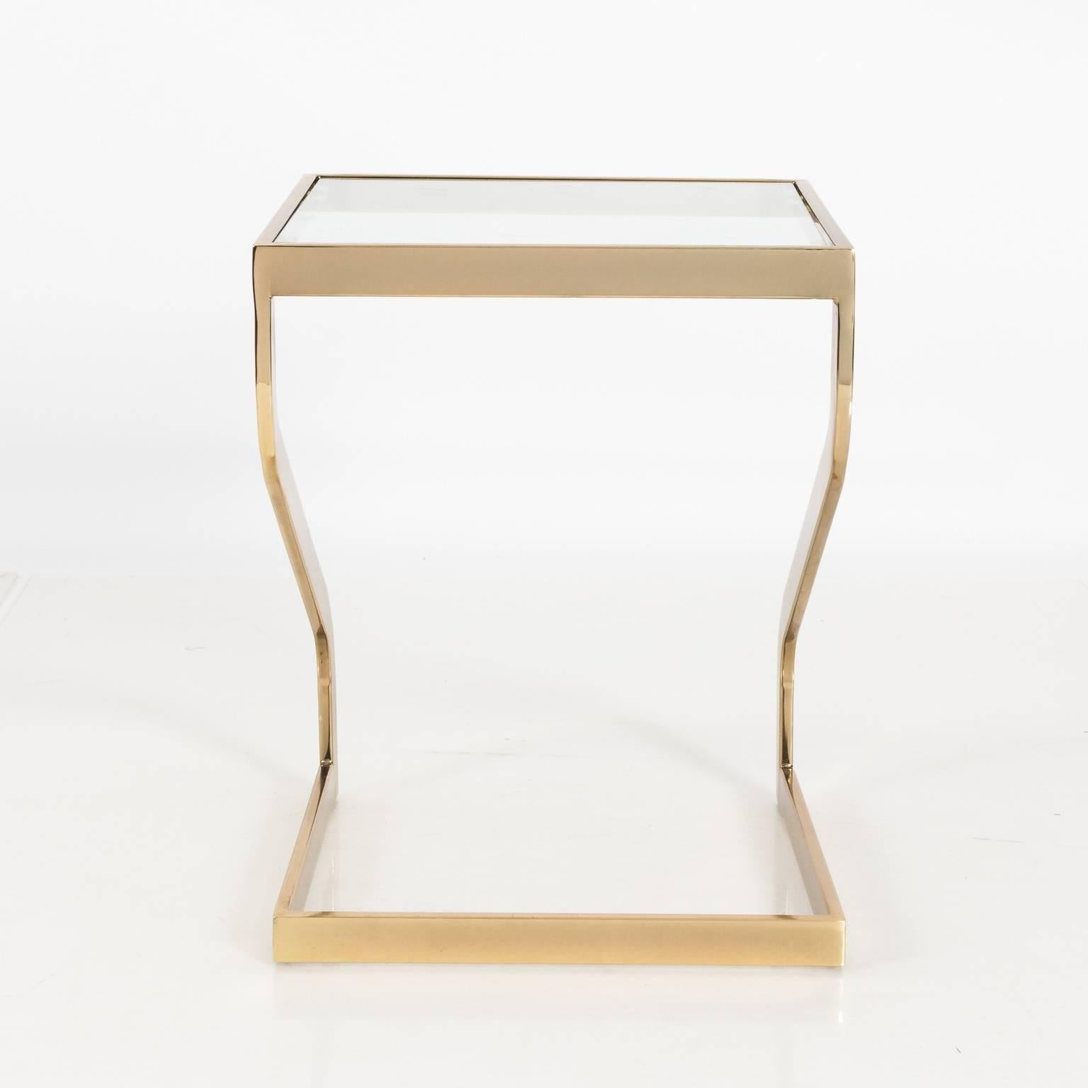Pair of brass cantilever base side tables with glass tops by the Design Institute of America in the manner of Milo Baughman, circa 1970. Note that the glass tops have minor chips.