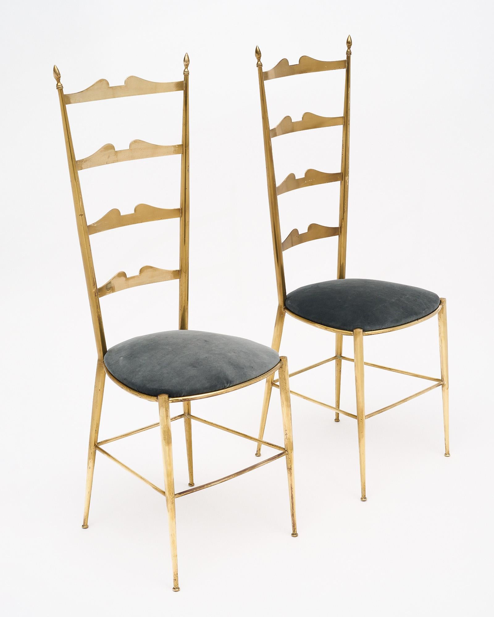 Pair of high backed chairs from Italy made of solid gilded brass with newly upholstered seats in a gray velvet blend. Chiavari chairs are named for the Italian city where they originated. The little town is located between Genoa and Cinque Terre and