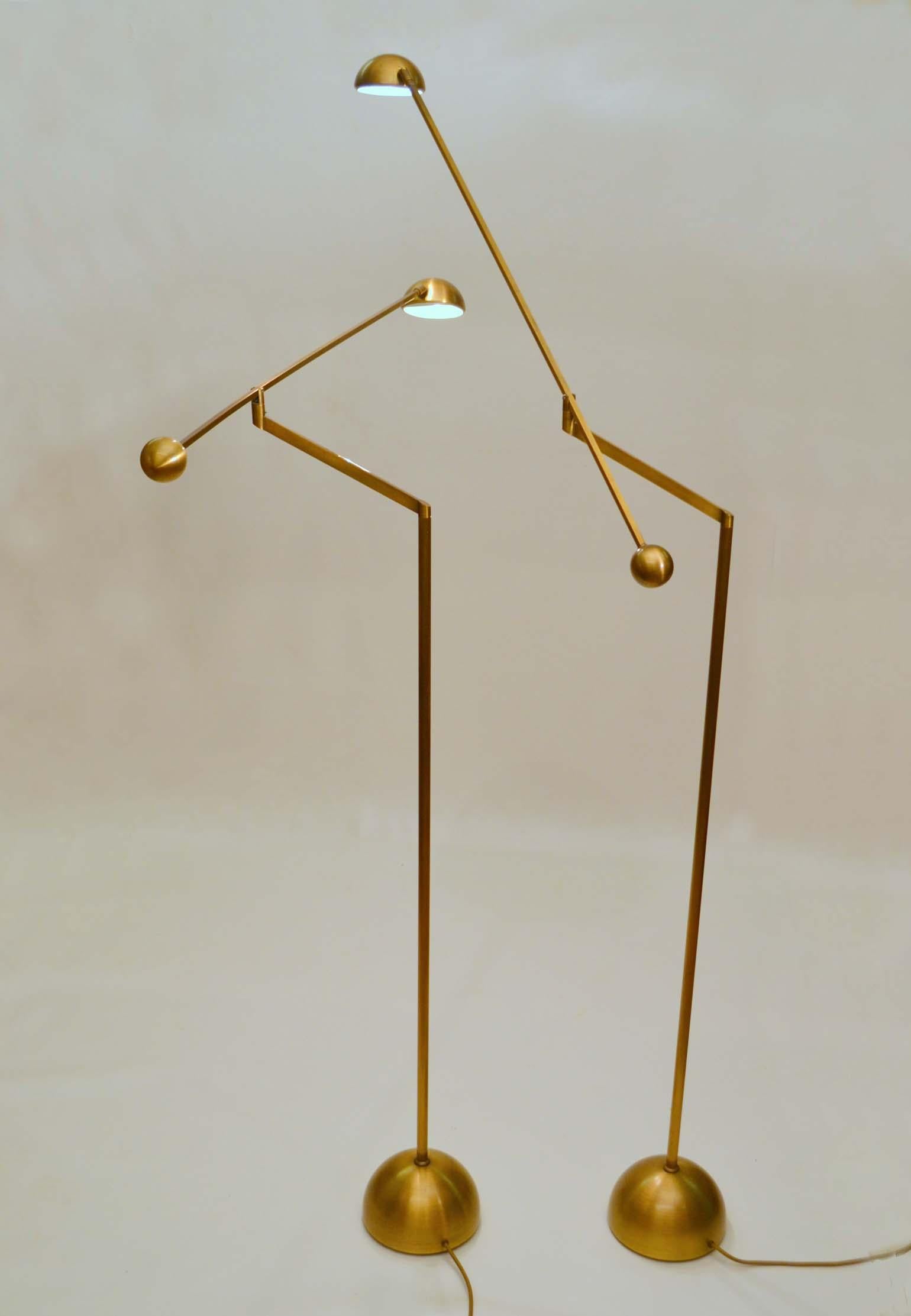 Pair of brass minimal counterbalance floor lamps are attached to a long arm holding a spherical bronze light source that is adjustable to 180 degrees. The arm sits on an angled stand which can also be pivoted at 180 degrees. This gives the lamps