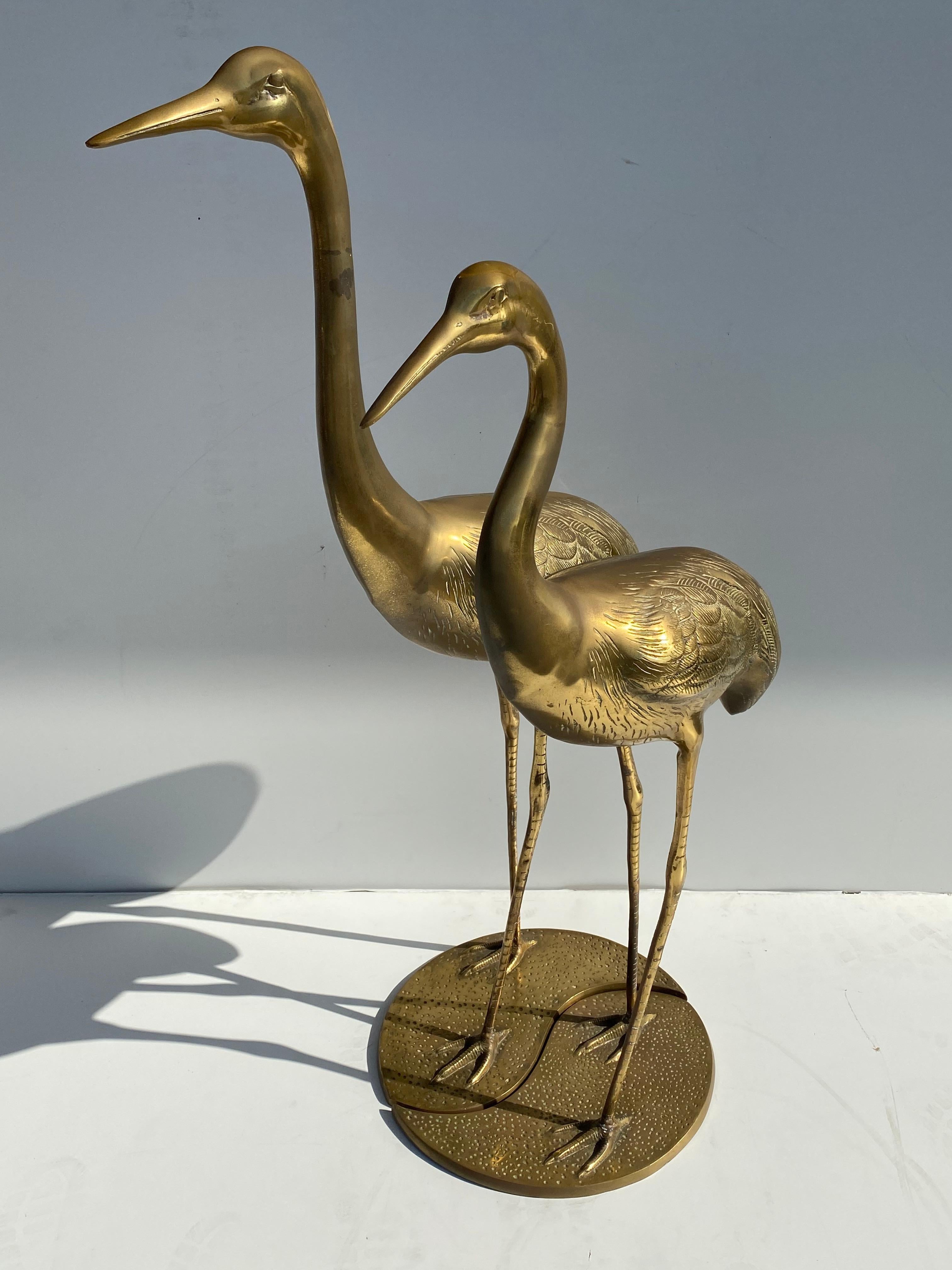 Pair of brass crane / stork interlocking sculptures. Taller crane is 47.5 and shorter 42