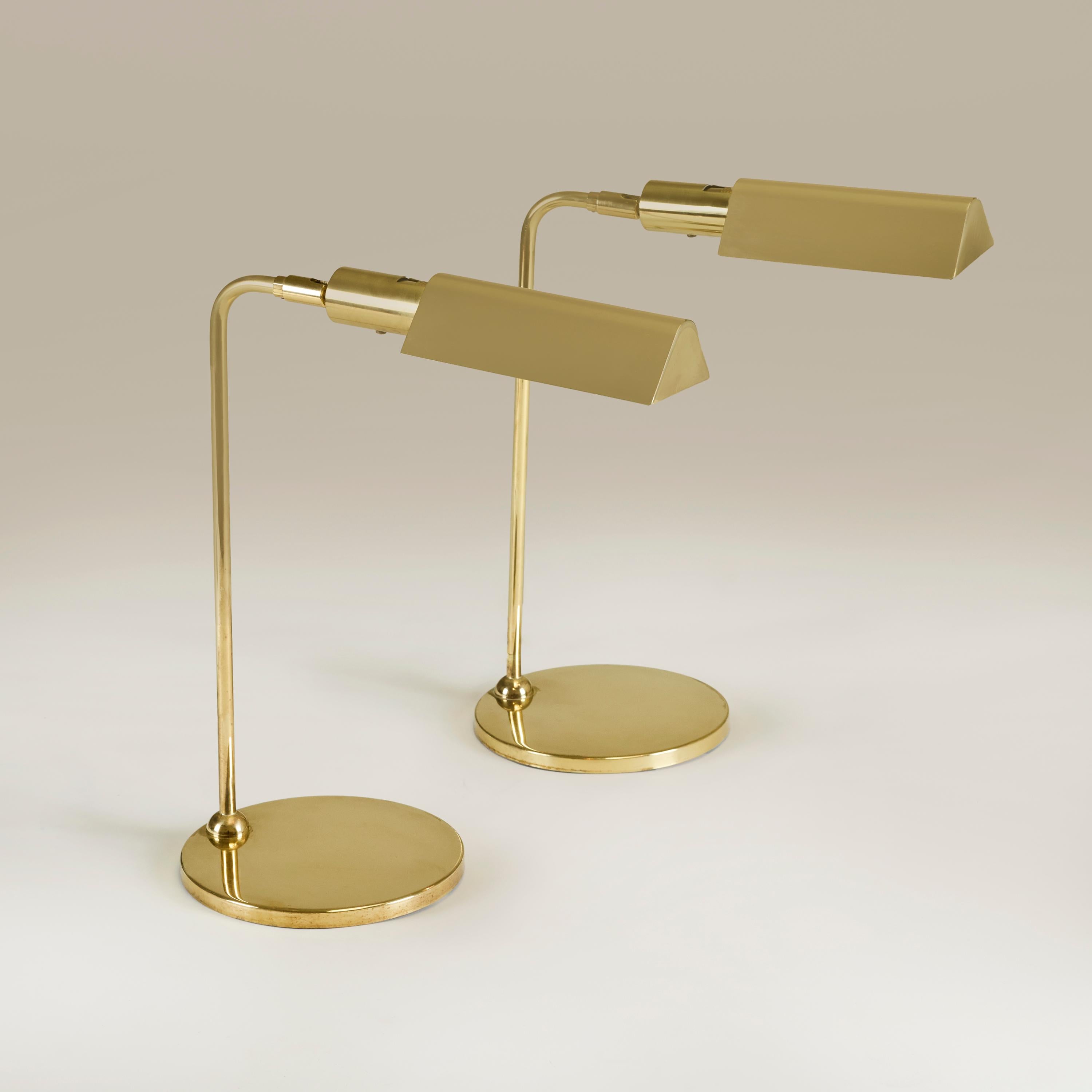 Chic pair of substantial brass lamps each with circular brass base, tubular curved arm and swivel brass shade.
