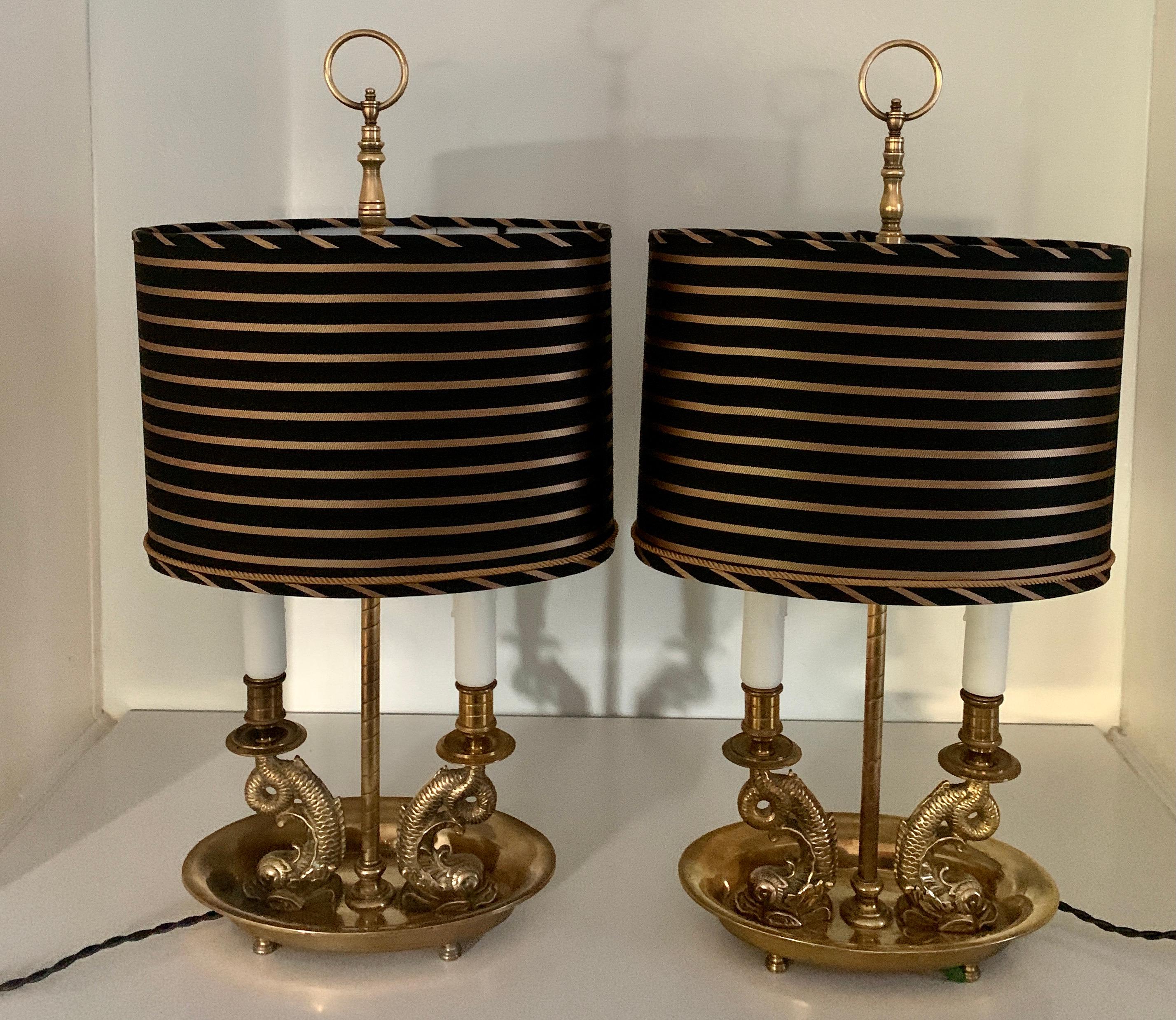 Acquired from a Bevelry Hills Estate, a pair of solid brass dolphin Bouillotte lamps with custom silk shades, the pair have been completely restored and rewired with 6' silk cords and custom designed and fabricated silk shades with gold rope cord.