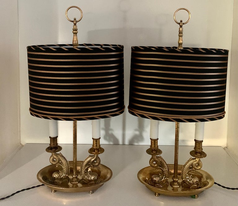 Pair of brass dolphin Bouillotte lamps with custom silk shades, the pair have been completely restored and rewired with 6' silk cords and custom designed and fabricated silk shades with gold rope cord. These were acquired from a Bevelry Hills