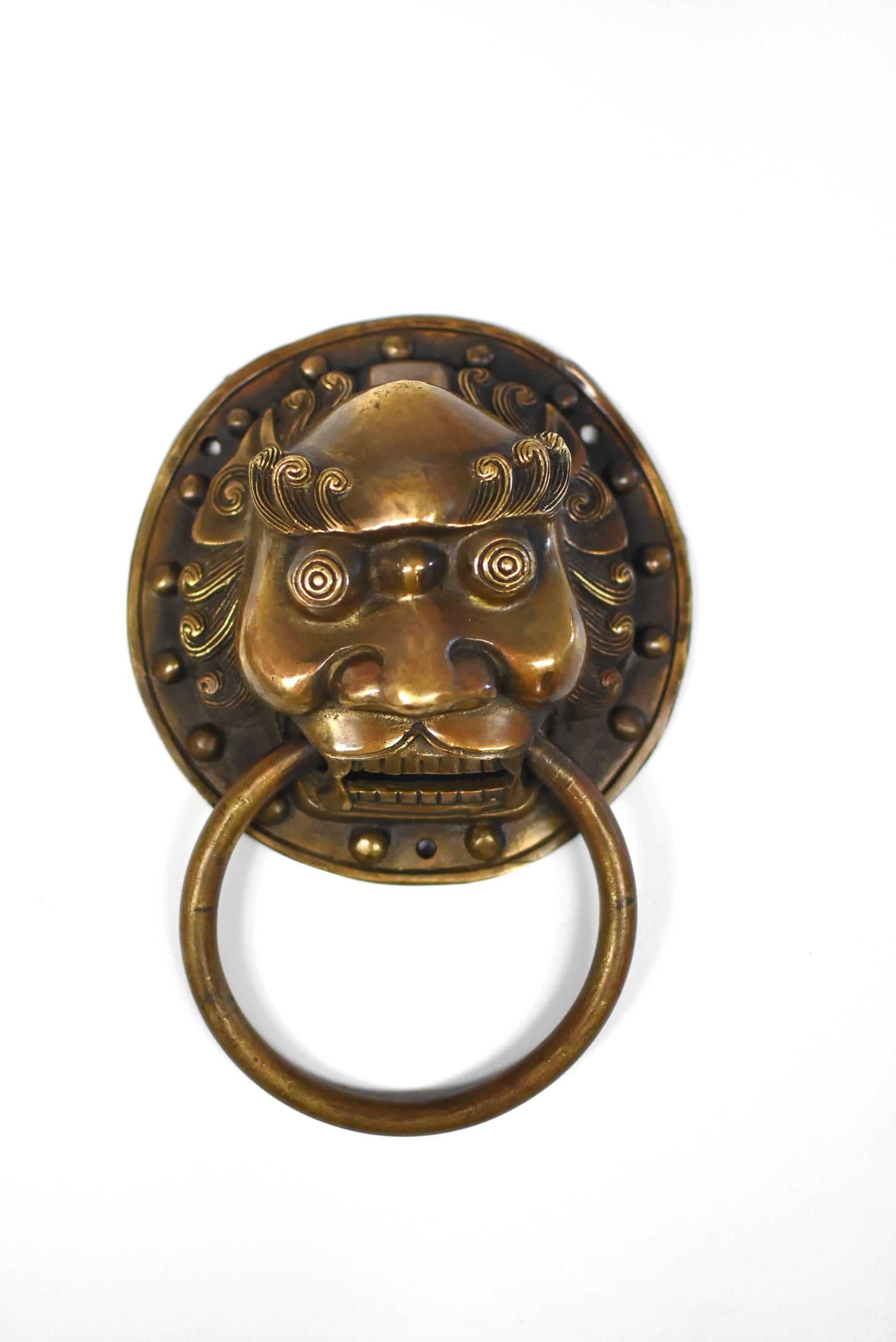 A pair of beautiful bronze warrior motif knockers. The mythical warrior has large bulging eyes above wide open mouth. Curly hair surrounding the face, repeated in the eye brows which flanks the prominent forehead. Heavy cheekbones echoes the