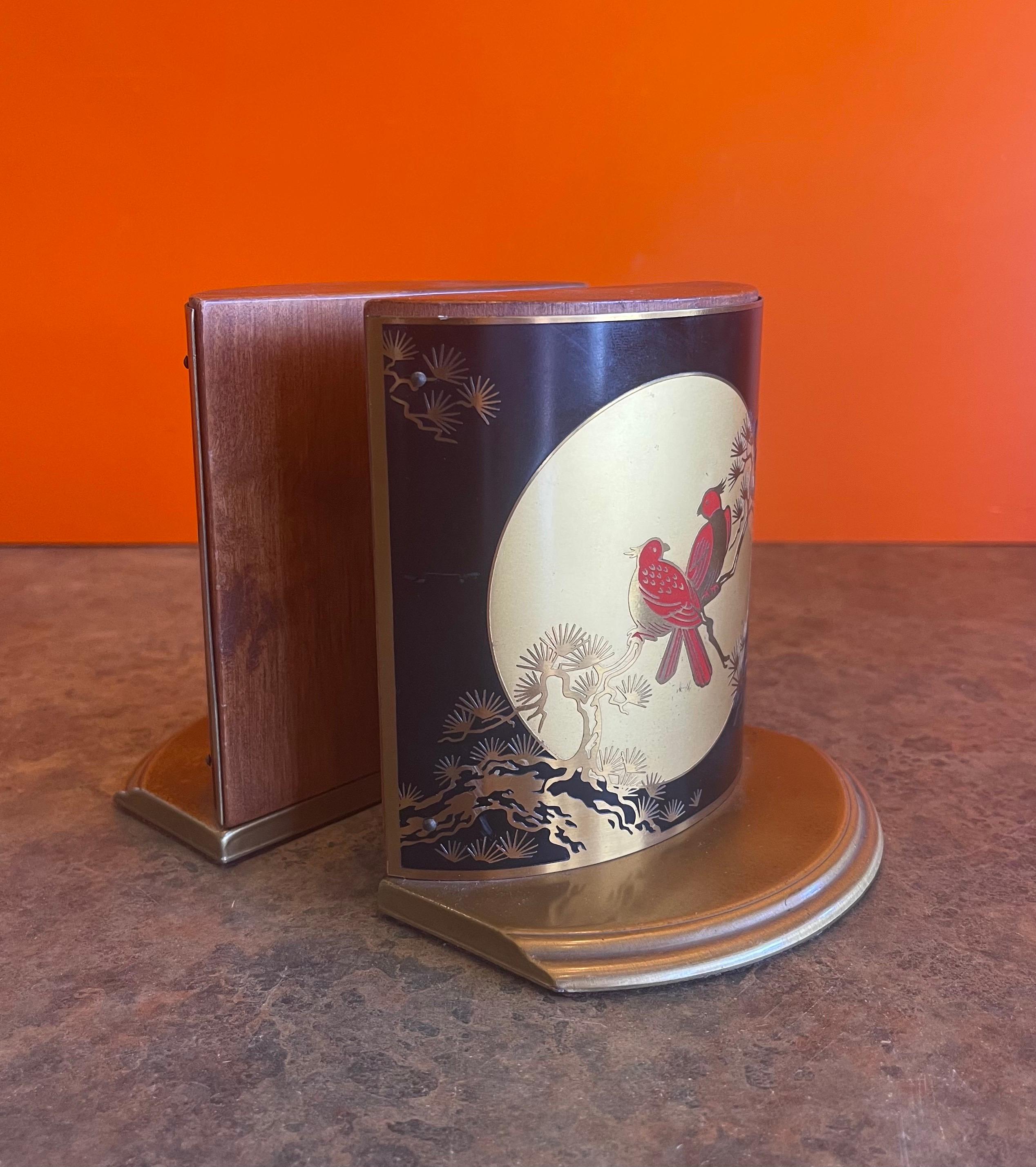 Gorgeous pair of brass, enamel and wood Asian style bird bookends by Grammes, circa 1950s. The bookends are made of solid wood and wrapped with a brass plate that has a colorful red bird enamel etching on it. The bookends feature felt pads along the