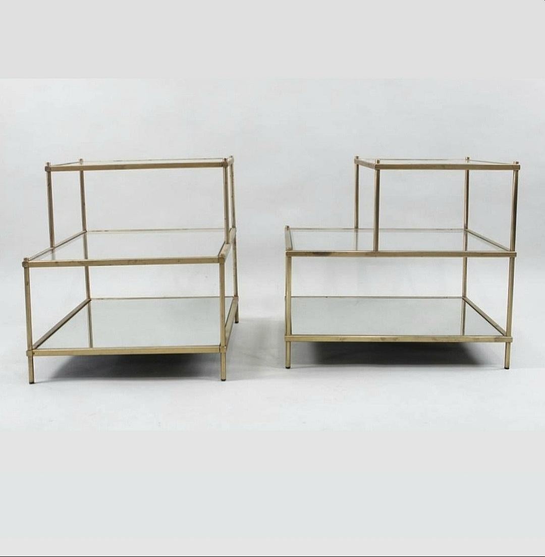 This is a very chic pair of 3 tier brass and glass side or end tables with a mirrored lower shelf and 2 graduated glass tiers above. This design has been recreated over the years, but none of this exacting quality. 
These beautiful little numbers