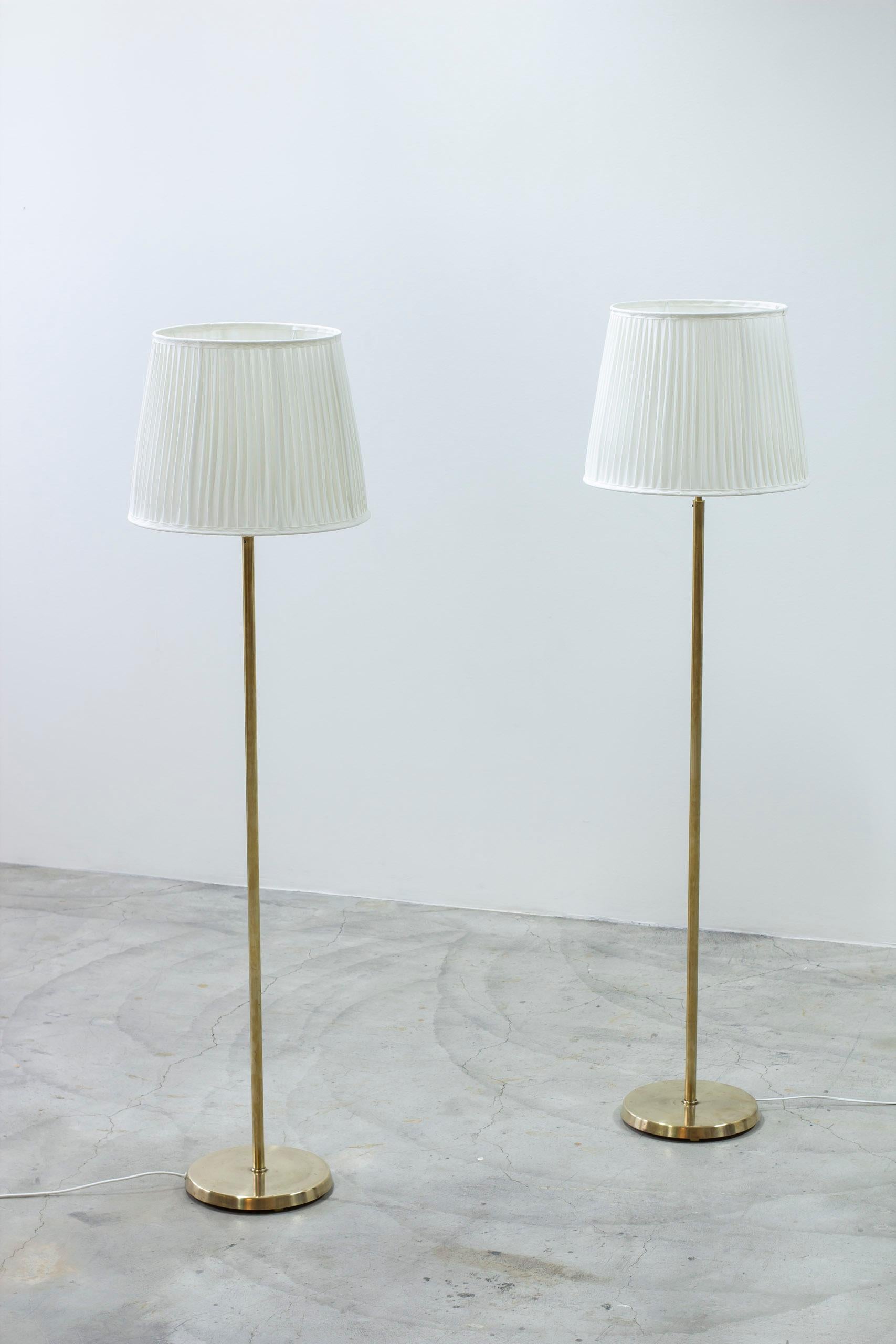 Paire de lampadaires produits en Suède par ASEA Belysning. Fabriqué dans les années 1950. Laiton poli et abat-jour neufs avec plis simples cousus à la main en chintz de coton. Interrupteurs d'éclairage sur le porte-lampe. Très bon état vintage avec