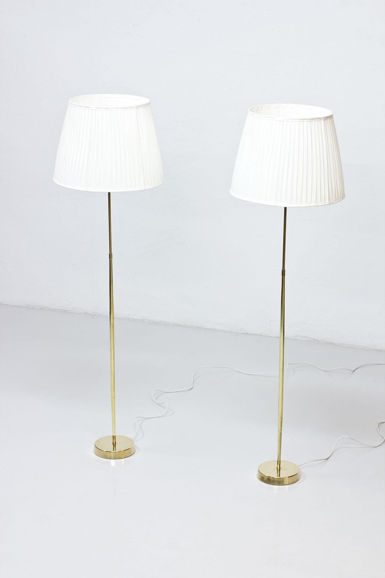 Ein Paar Stehlampen, hergestellt von ASEA Belysning in Schweden in den 1950er Jahren. Die Lampen bestehen aus einem polierten Messingstiel mit handgefalteten Lampenschirmen aus cremefarbenem Chintzstoff. Neu verkabelt mit Lichtschalter an den